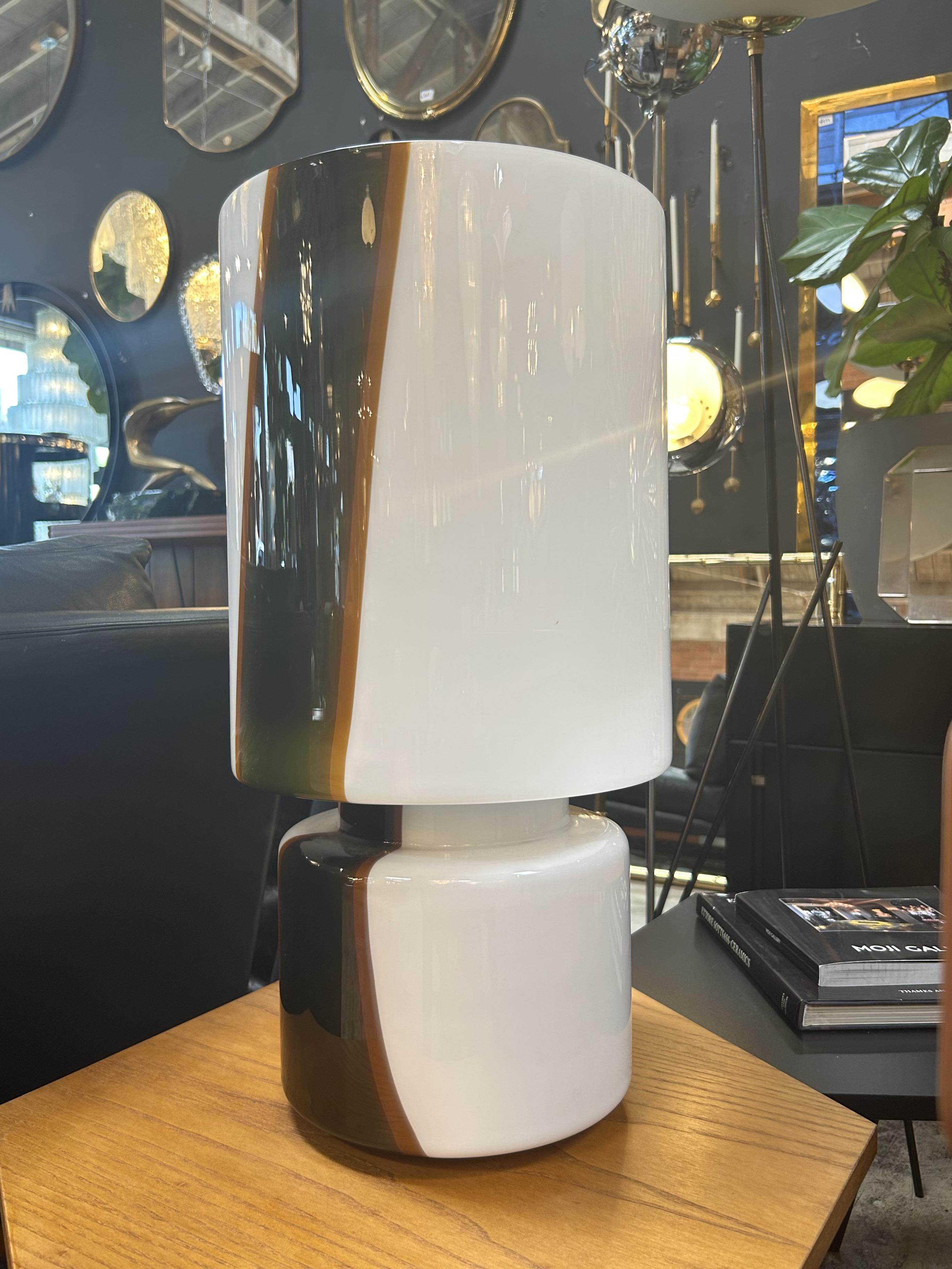 Murano glass table lamp crafted in Italy during the 1970s, this piece exemplifies the artistry and innovation of Venetian glassmaking. The lamp features a bold, cylindrical form composed of two stacked elements—each expertly blown in thick glass