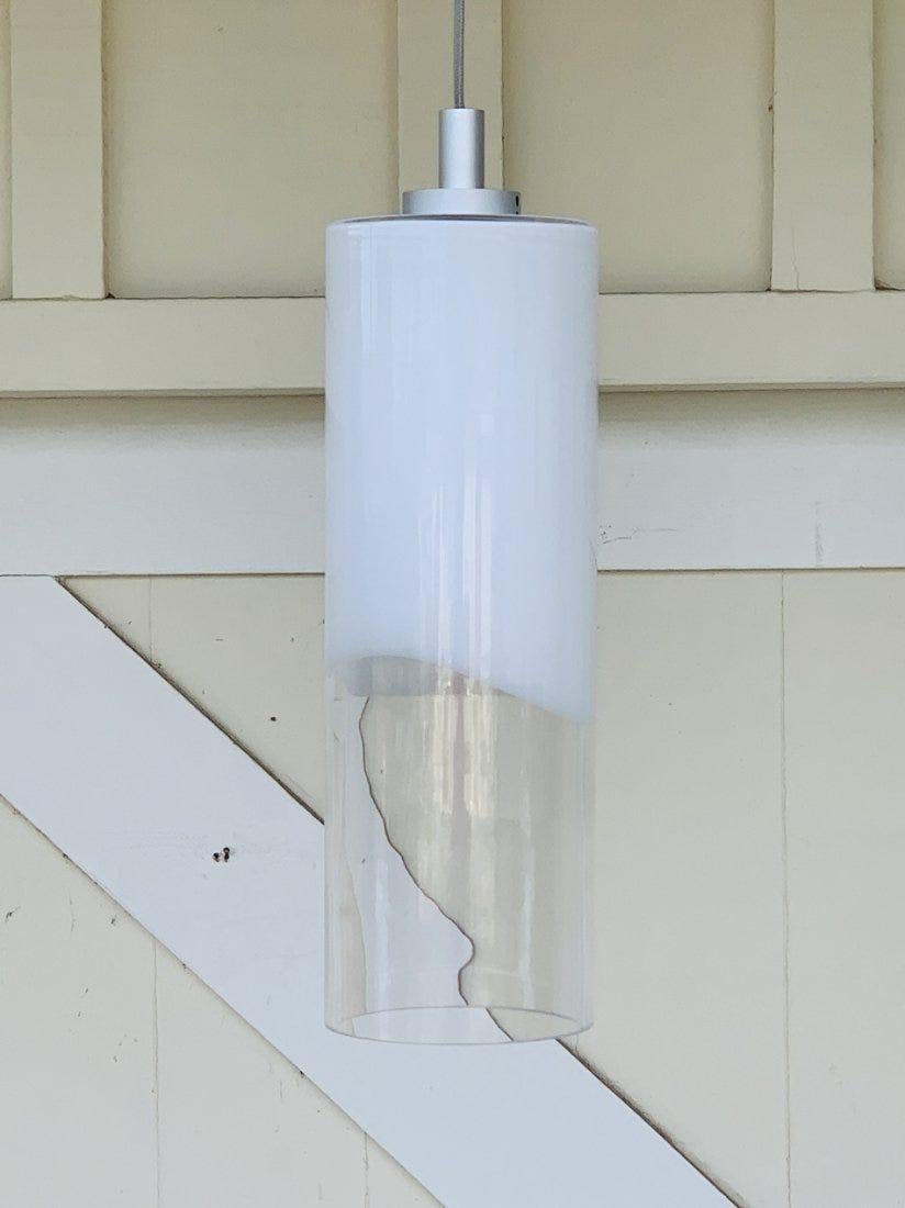 Introducing the Murano Style Cylinder Pendant Light, a sophisticated addition to your home décor that effortlessly combines elegance and modernity. This exquisite hanging light features a sleek white cylinder shade, elegantly suspended from a sleek