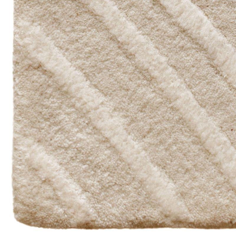Hypnotizing in its concentric, raised design inspired by the invisible lines traced by whirlwinds, this rug is a precious piece carefully hand-tufted by coupling wool and cotton yarns that is sure to capture the eye in a contemporary home. Please