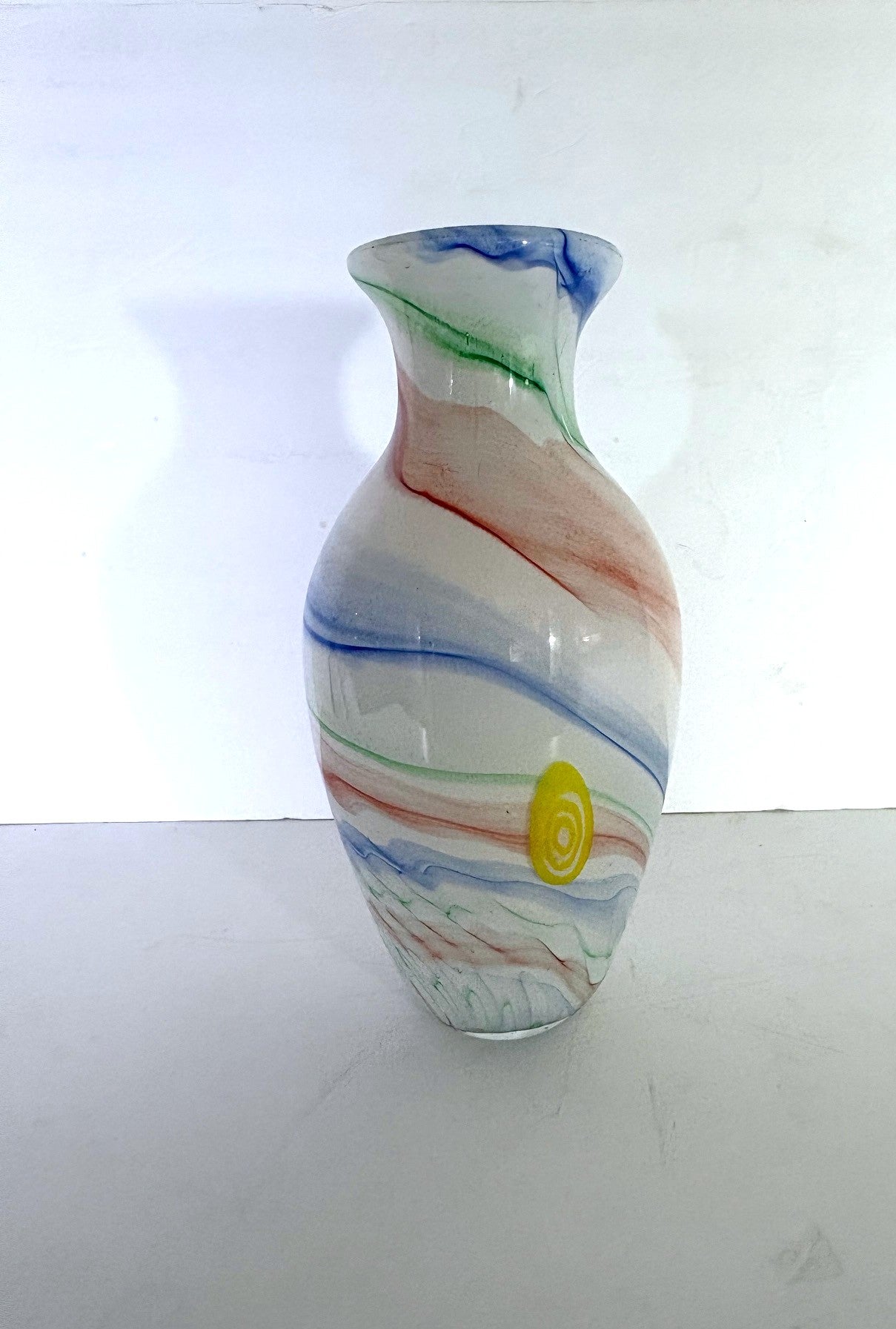A hand blow Murano vase with a swirl pattern and two yellow dots.