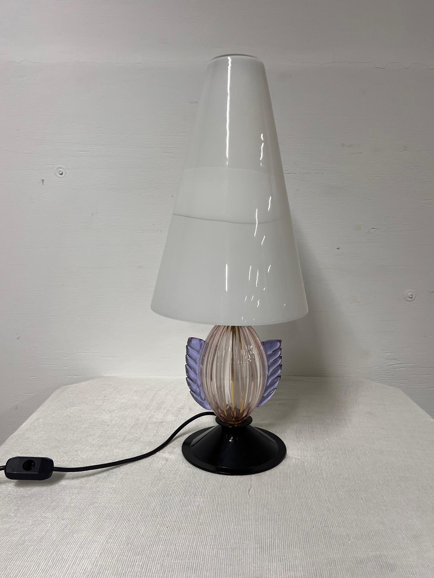 Glass Murano Table Lamp
1970s. 
Circular base, ribbed stem decorated with hot-pressed details, conical diffuser in milk glass with the label
“Glass made by Murano masters - Made in Italy”.
Needs to be rewired 