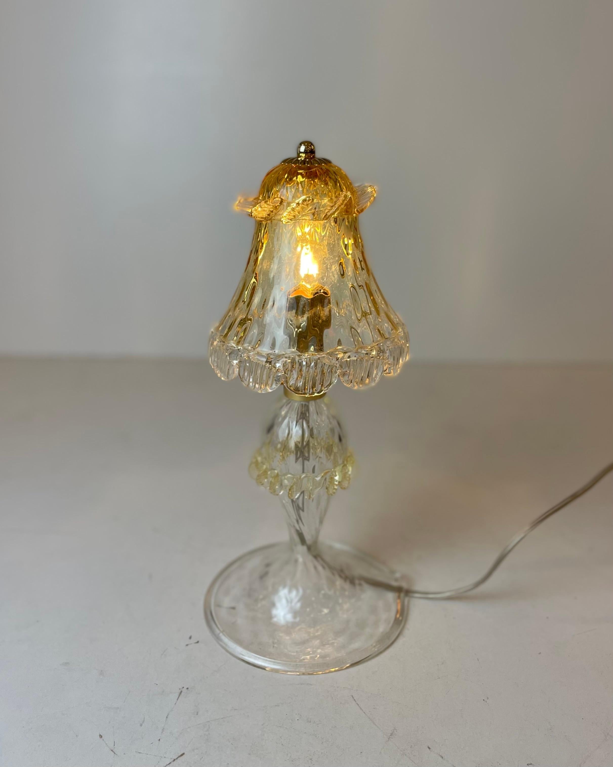 A cute, small table lamp made of beautifully shaped, clear, and honeyed Murano glass on a golden metal structure. Designed in the style of the famous Venetian brand Barovier & Toso in the 1980’s.
-
Produced in: Murano, Venice, Italy
Design period:
