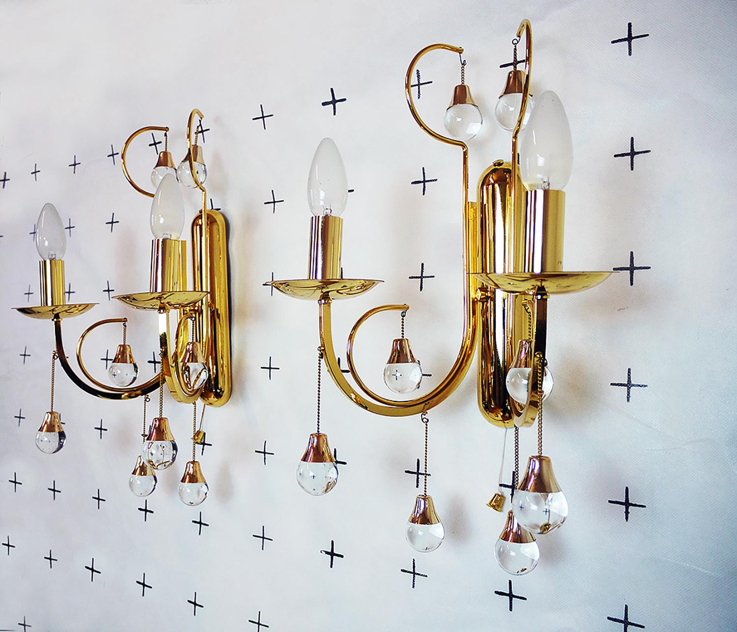 Élégante paire d'appliques murales en forme de goutte d'eau avec des sphères en verre de Murano, chacune sur une monture en laiton plaqué or. Les verres suspendus ressemblent à des gouttes d'eau. Les appliques murales brillent d'un bel éclat et