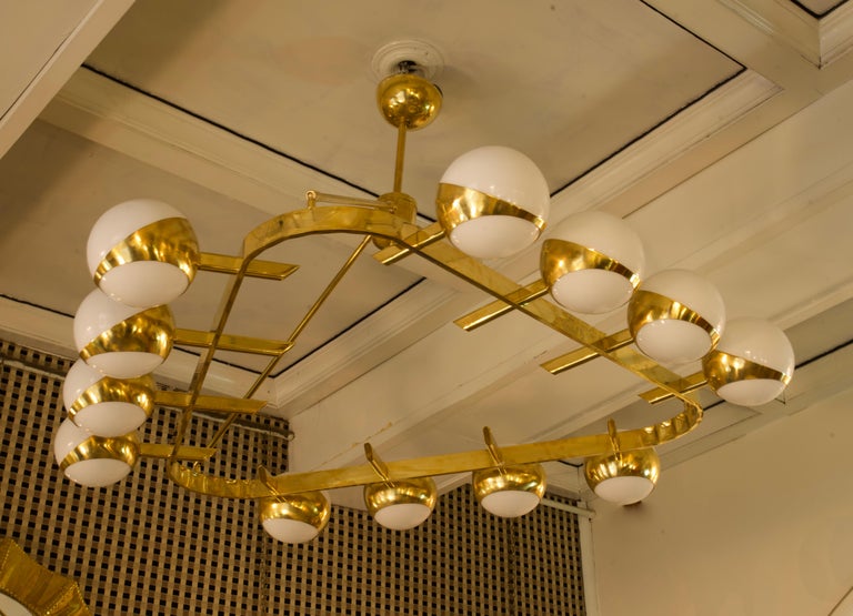 Superb chandelier for its characteristic triangular structure, unique design for the brass housing of the spheres.

The chandelier has a polished brass structure, triangular in shape with rounded corners. On each side there are four housings for