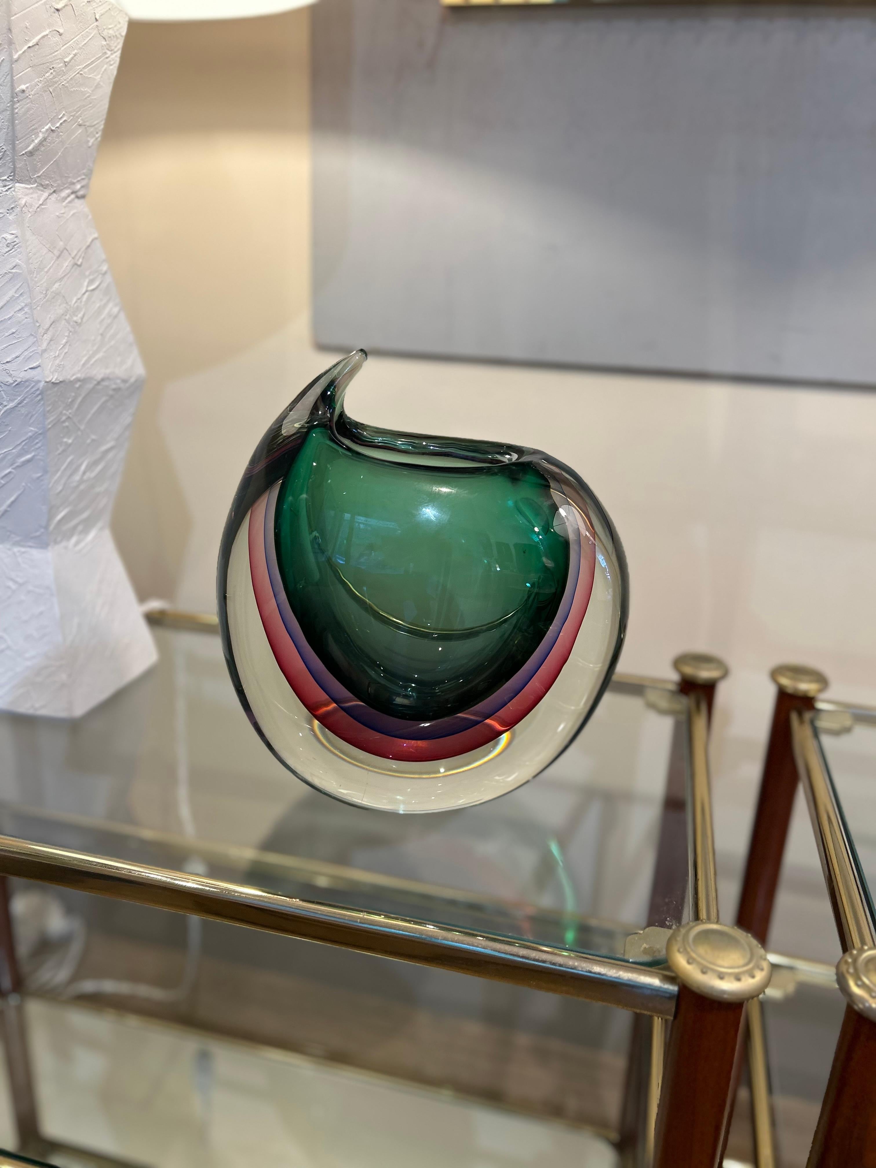 Ce vase est réalisé selon la technique du sommerso, typique de Murano, qui consiste à superposer plusieurs couches de verre coloré. Cette méthode a été popularisée par des maîtres verriers tels que Seguso, Flavio Poli et Mandruzzato.
Forme : Le