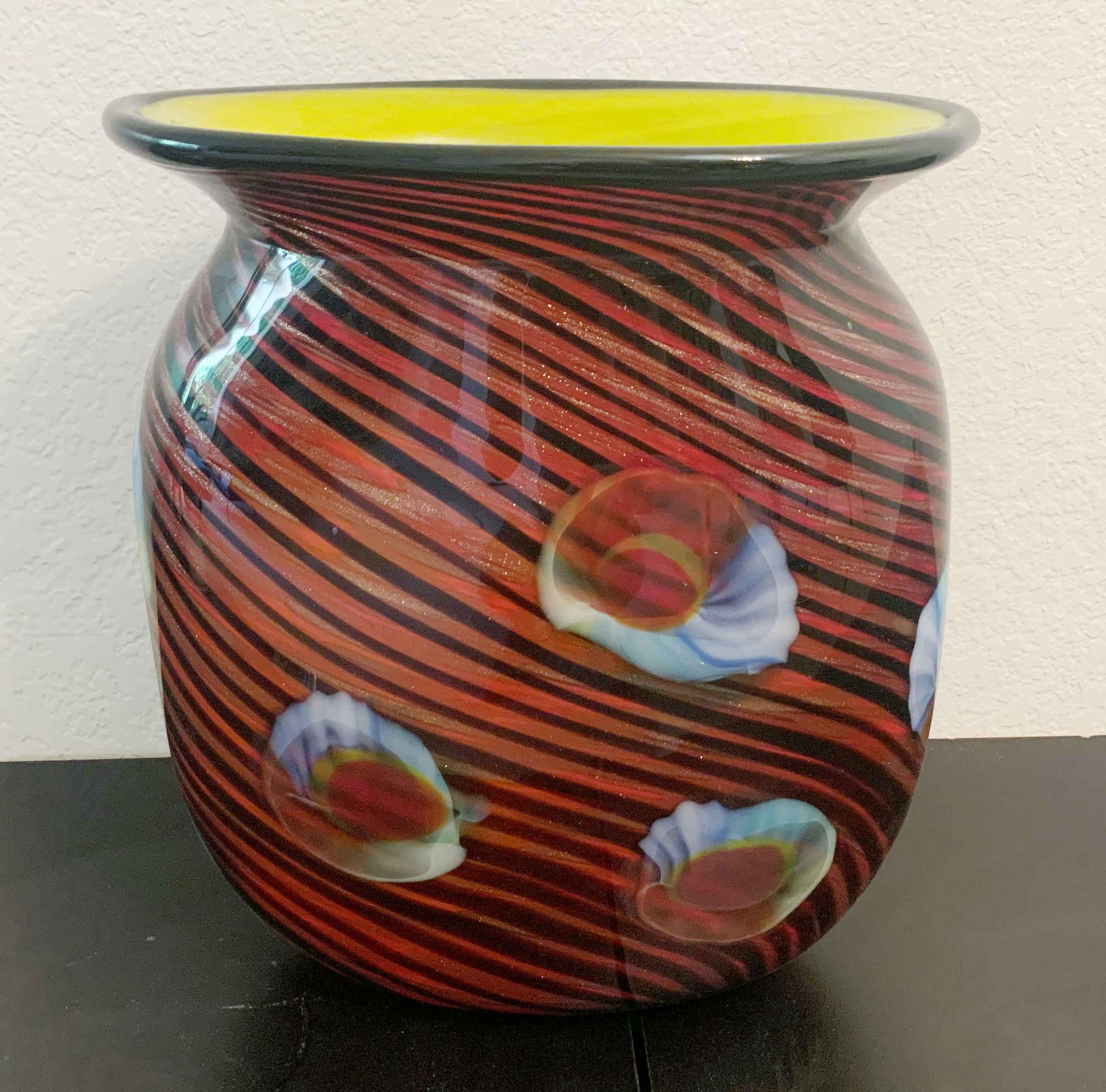 Vase aus italienischem Murano-Glas mit dunkelrotem Äußeren und gelbem Inneren, mundgeblasen mit schwarzen Streifen, durchsetzt mit Goldflecken und verziert mit muschelartigen Figuren / Made in Italy, circa 1970er Jahre
Maße: Höhe 13 Zoll, Breite 12