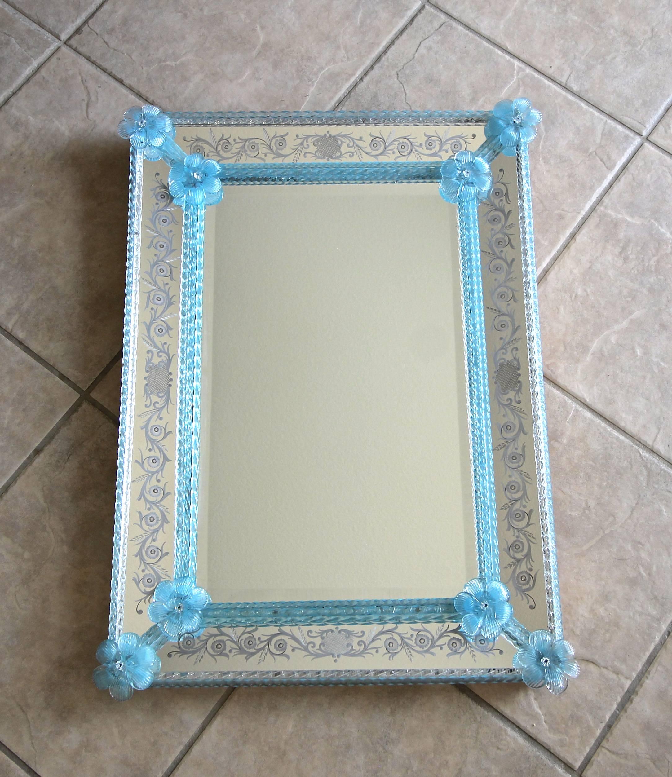 Attractive Italian Venetian bevelled edge mirrored wall mirror with light blue glass flowers and finely twisted rods. Rods are combination of blue and one row of clear rods. Surrounding the mirror is a detailed scroll form reverse etched border.