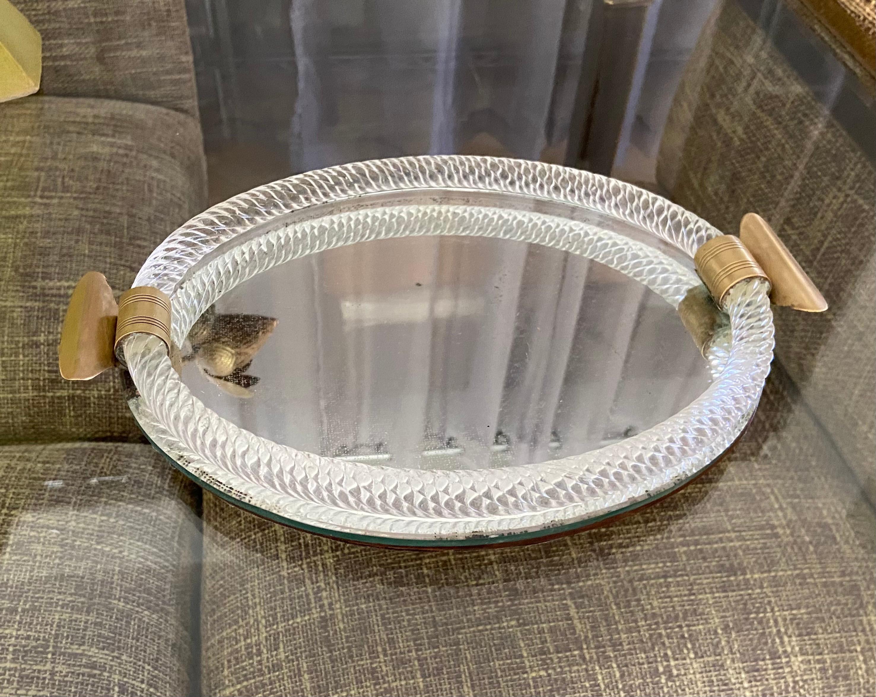 Smaller scale Murano oval shaped finely twisted clear glass vanity tray. Tray has nice solid brass fittings and mirrored glass bottom mounted on composite wood backing. (Width with handles 12.75