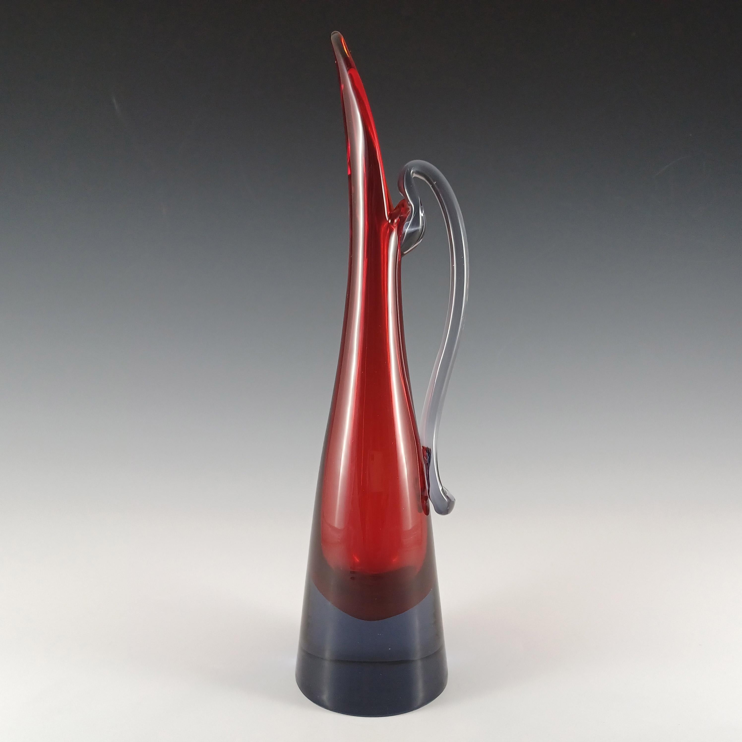 Un alto vaso a stelo in vetro veneziano nello stile di una brocca, realizzato sull'isola di Murano, vicino a Venezia, in Italia. In una straordinaria combinazione di vetro rosso racchiuso in vetro blu/violetto, utilizzando la rinomata tecnica