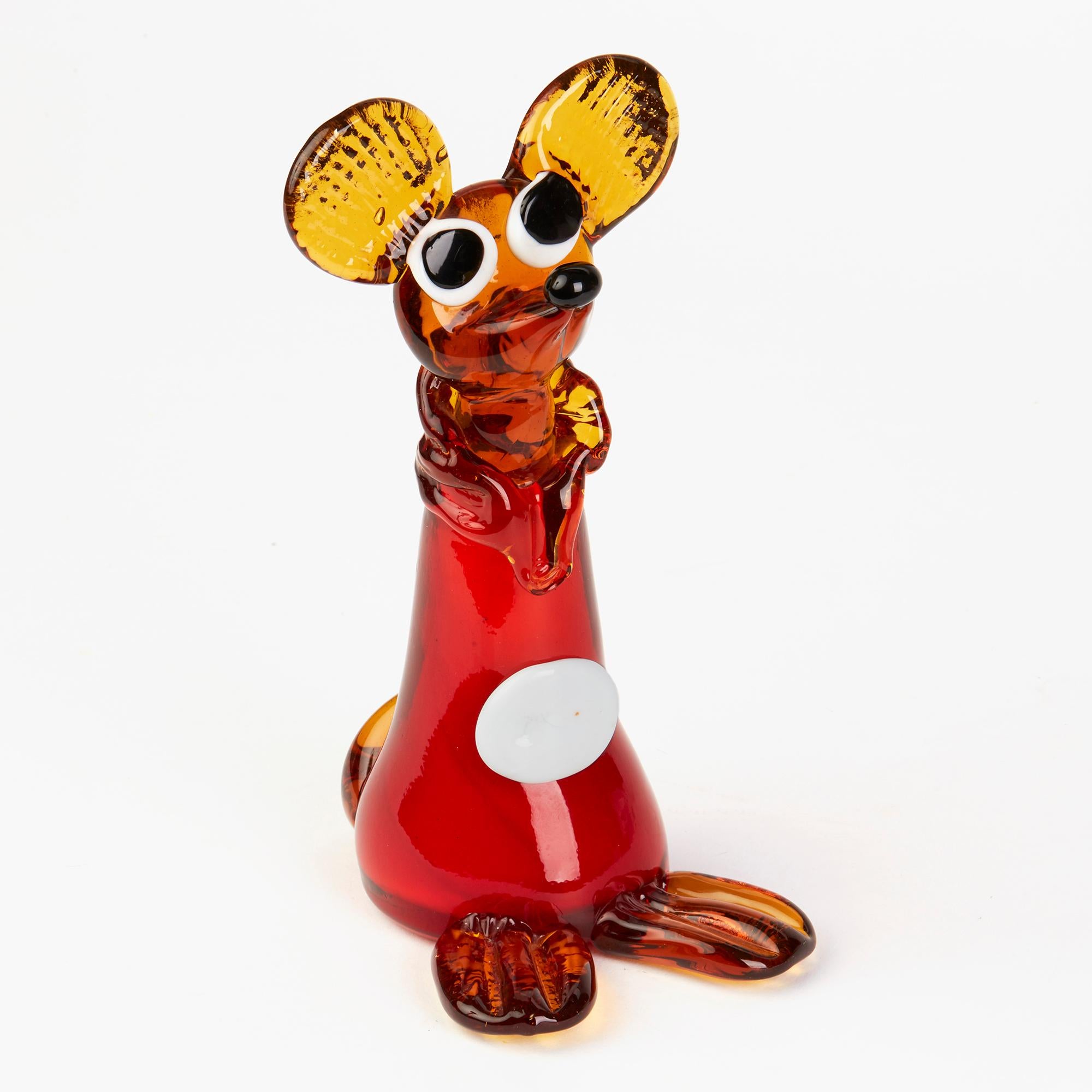 A delightful vintage Italian Murano novelty glass mouse figure standing wearing a long 'robe' in red cased in amber glass with a large white button with large amber glass feet, tail and head with a black glass nose and black on white glass eyes