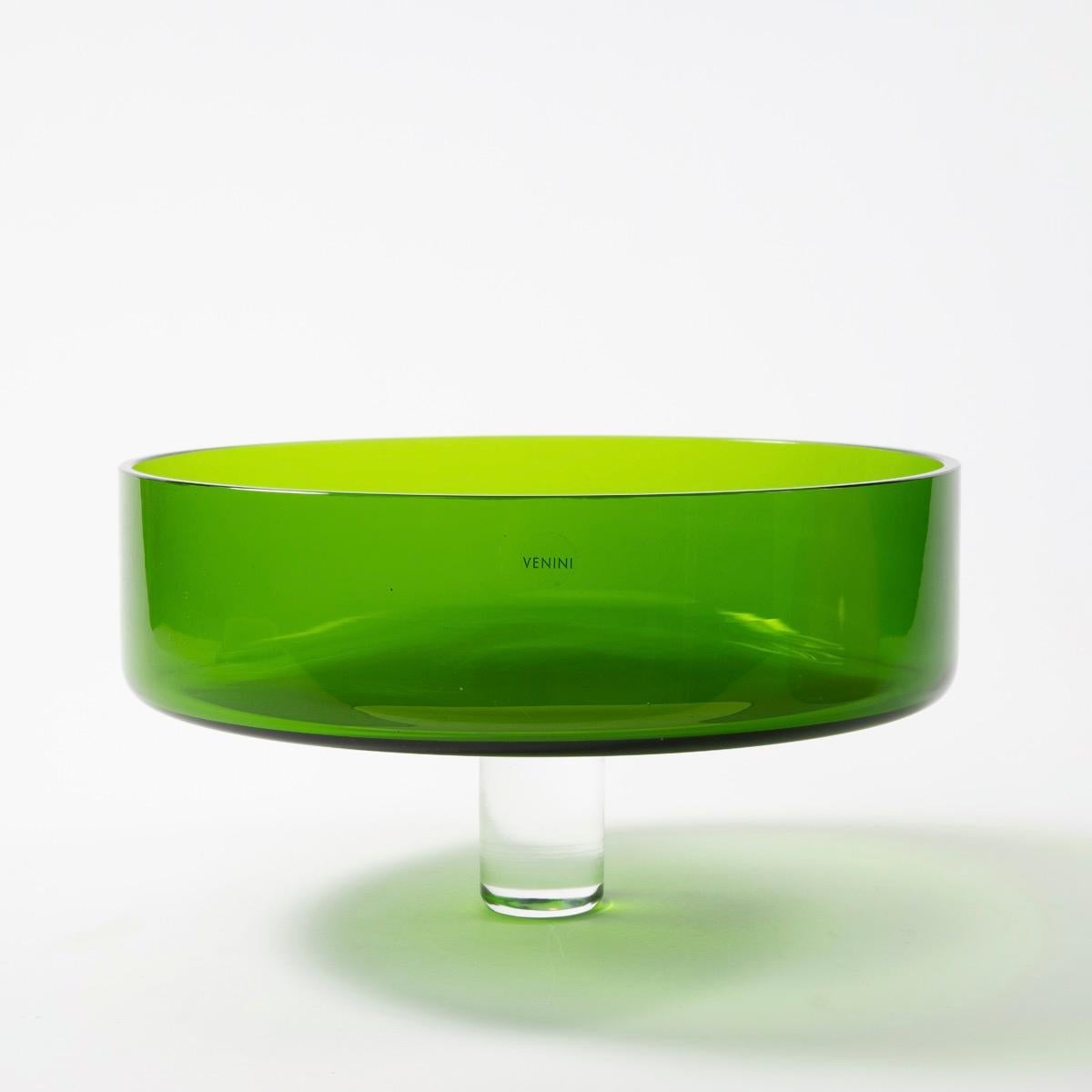Puzzle is a piece arising from a series of vases and centerpieces imagined by Ettore Sottsass for Venini at the end of the 2000s. 
The base is made of glass and has a coral colour. The upper part is a bright green glass tray, on which a shaft was