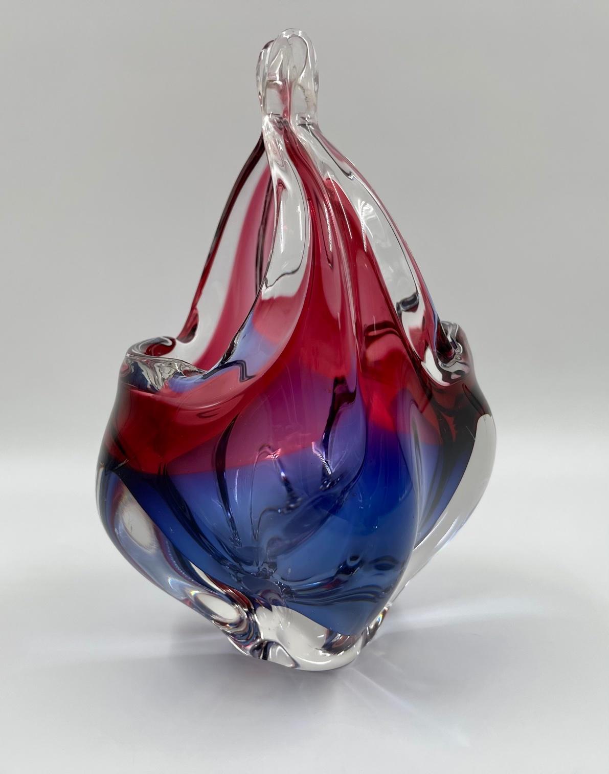 Wir präsentieren einen Kerzenkorb aus tschechischem Kunstglas, der 1960 von Josef Michael Hospodka für die renommierte Glasfirma Chribska hergestellt wurde. Der Halter verfügt über ein kompaktes, zweifarbiges Glas in den Farben Blau und Rot. Dieses