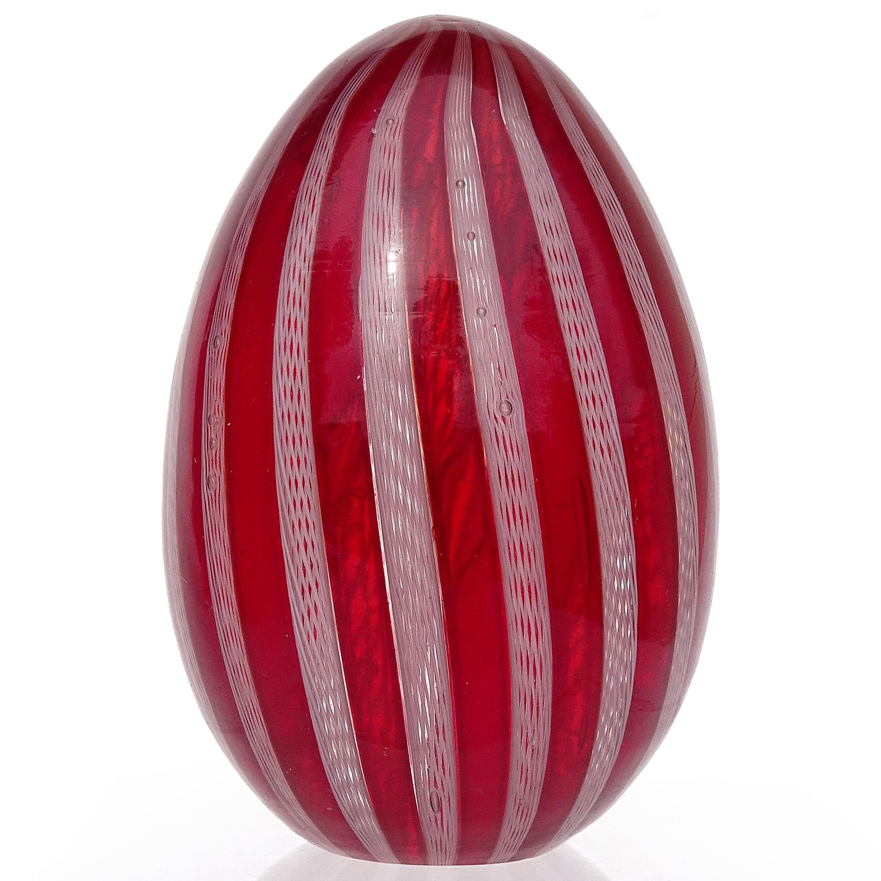 Beautiful vintage Murano hand blown red and white ribbons Italian art glass egg shaped paperweight. Attributed to the Fratelli Toso company. The paperweight is made with deep red 
