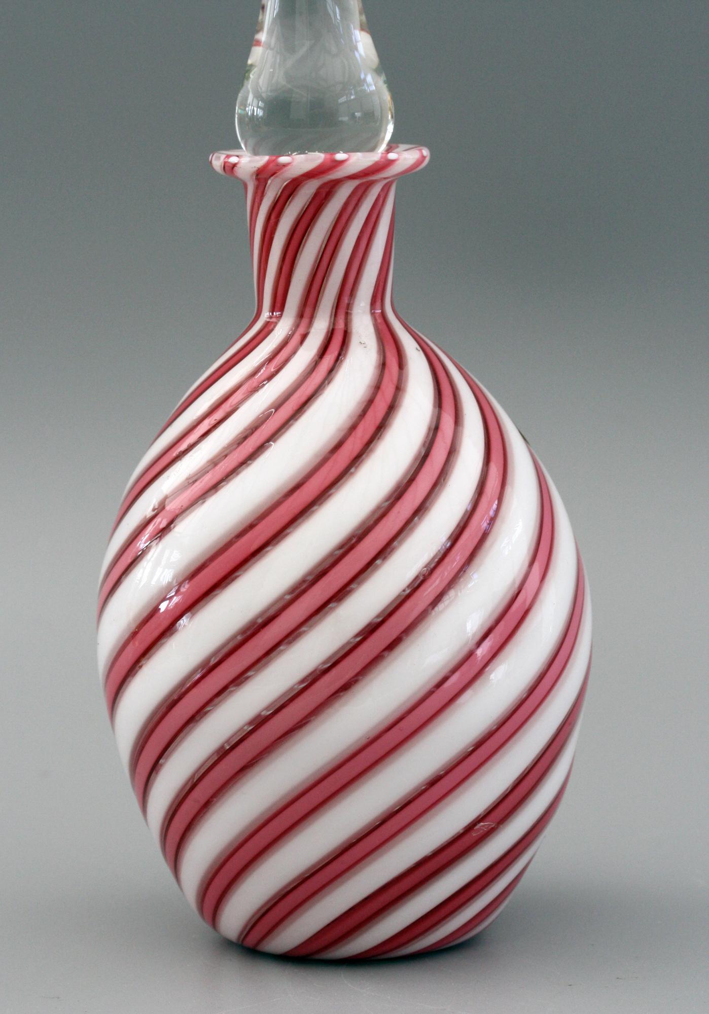 A very stylish vintage Italian Murano hand blown art glass scent bottle and stopper in pink and white ribbon design dating from the 20th century. This elegant bottle has an oval shaped body with narrow funnel shaped neck with a fold back top rim