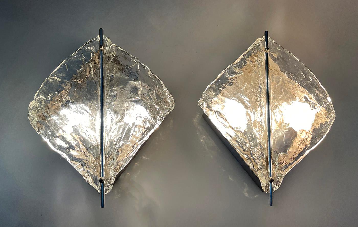 Lampade da parete di Murano di Zero Quattro, anni '70

Lampade da parete in vetro soffiato trasparente a rilievo a forma di ala con al centro un lungo perno verticale cromato attaccato a un retro in metallo color cromo spazzolato. 2 lampadine sono