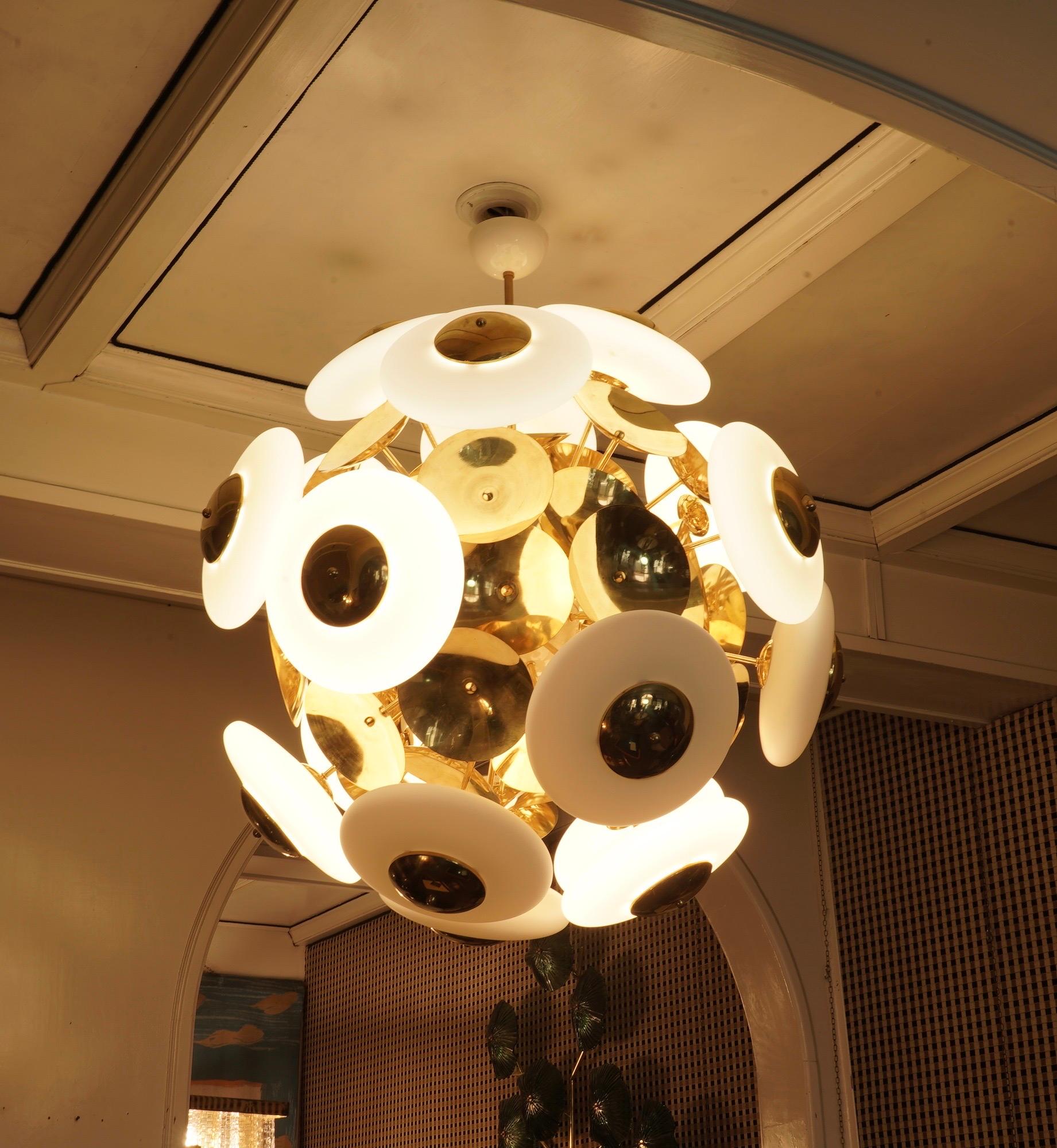Un fantastico punto di colore bianco e oro, dal design sorprendente per la forma molto particolare di queste sfere appiattite in vetro bianco e per i fantastici dischi in ottone. Molto elegante, arreda e decora l'intera stanza.

Il lampadario è