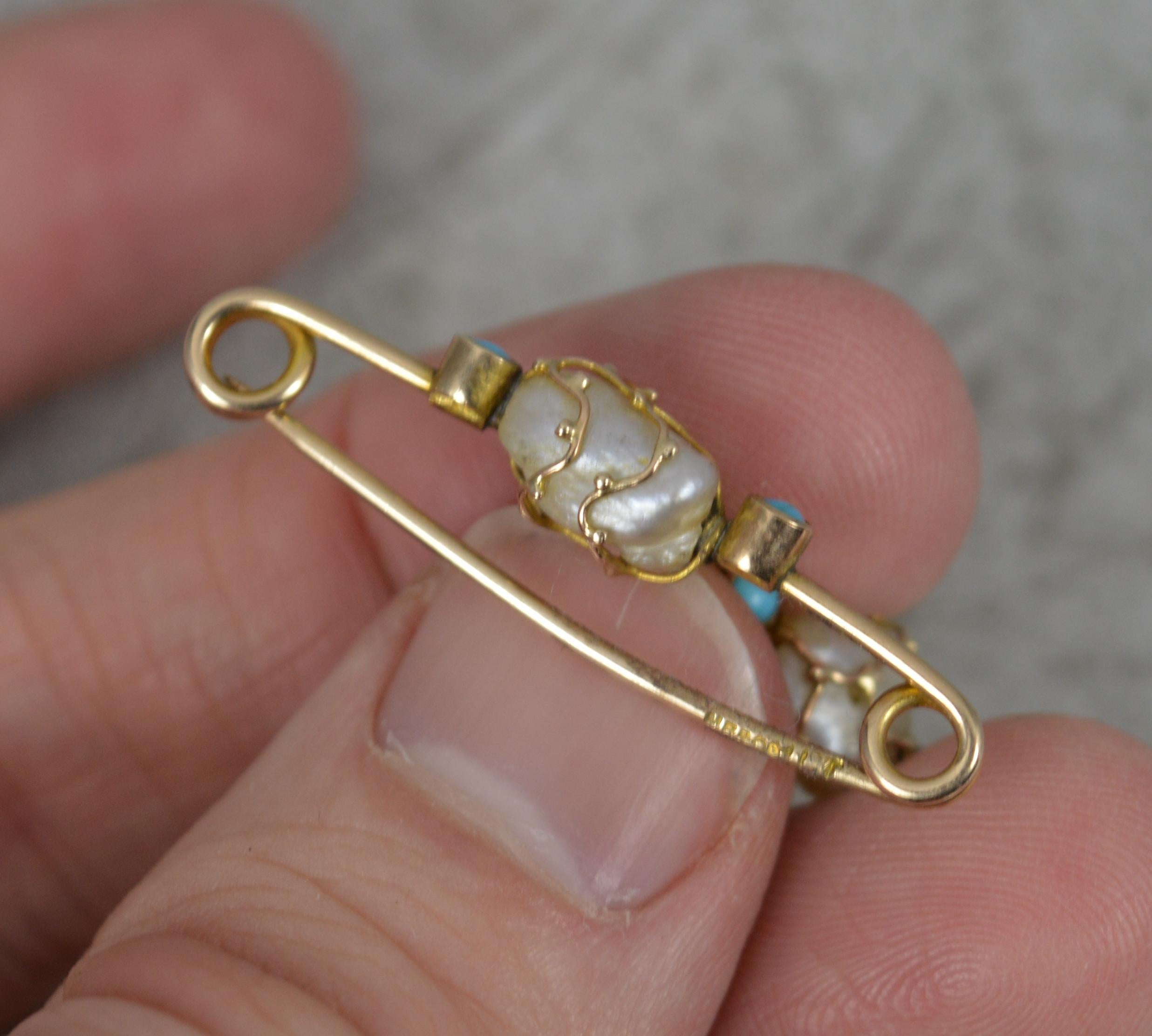 A beautiful true antique brooch.
​Solid 9 carat gold example. Designed with a caged free form pearl to pin, with turquoise each side. Below hangs a further caged free form pearl on a lavalier chain.
2.1 grams, 3.3cm approx.
By Murrle