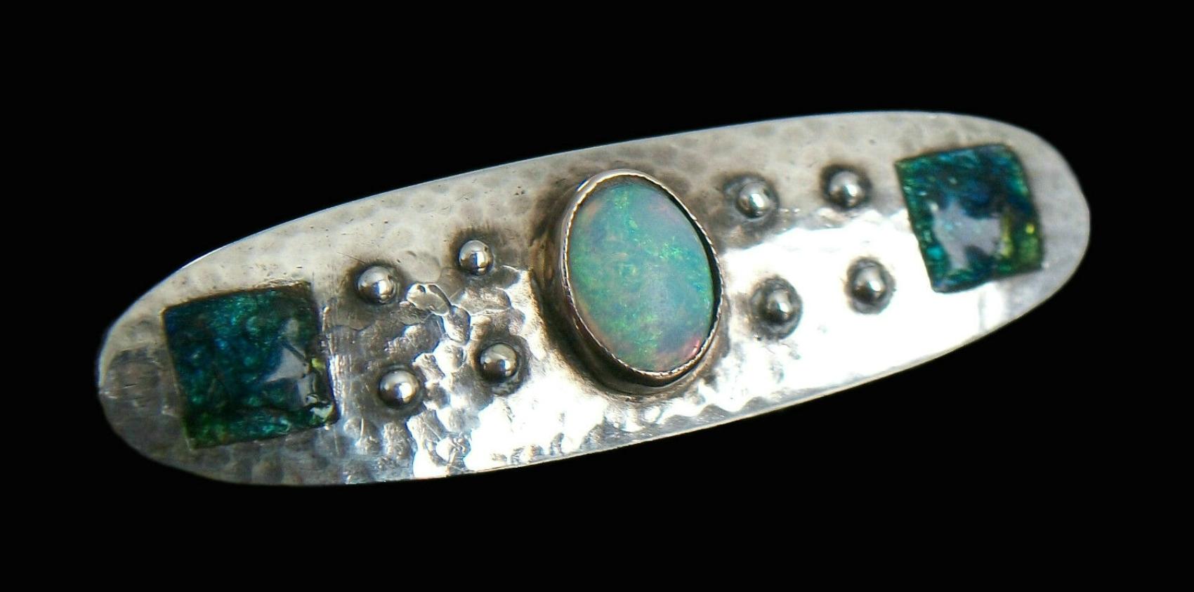 MURRLE BENNETT & CO. - Rare Arts & Crafts fine silver brooch - hand hammered finish with rivet details - central oval cabochon opal bezel set in pink gold - blue and green enamel panels to each end - handmade 'C' clasp - hallmarked and signed 'MBCo'