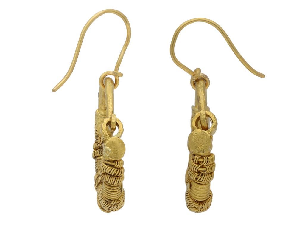 Ancient Greek wirework earrings. A matching pair, each composed of a substantial solid gold hoop, decorated with tightly coiled fine wires around the hoop, interspersed with further intricate wirework coils and flattened circular gold details to the