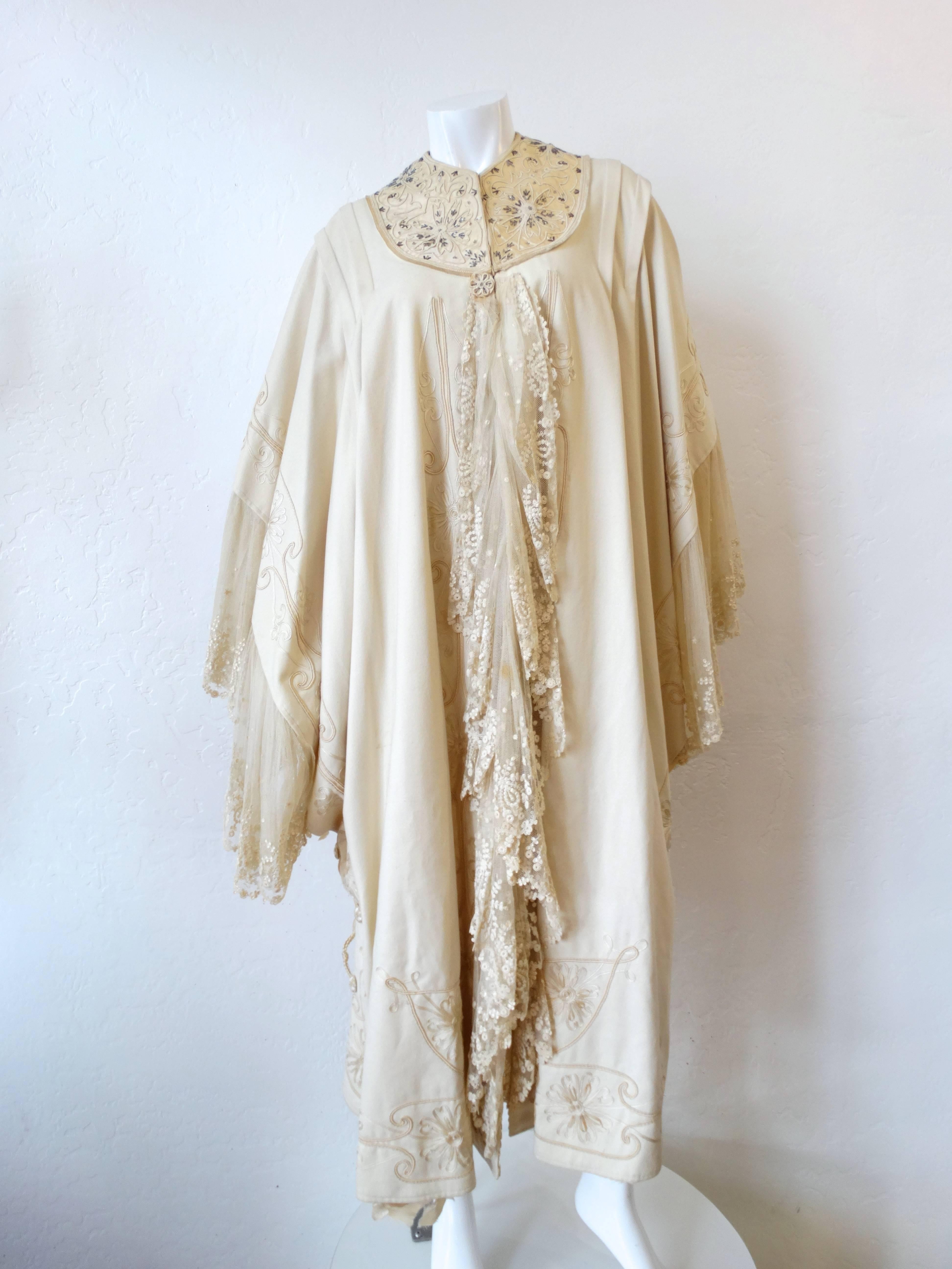 Incredible 1930s Museum Quality cape! Huge angel wing sleeves lined with layers of intricate cream lace. Cream silk yoke around the neck features detailed botanical embroidery and silver beaded accents. Hook and eye closures up the front of the