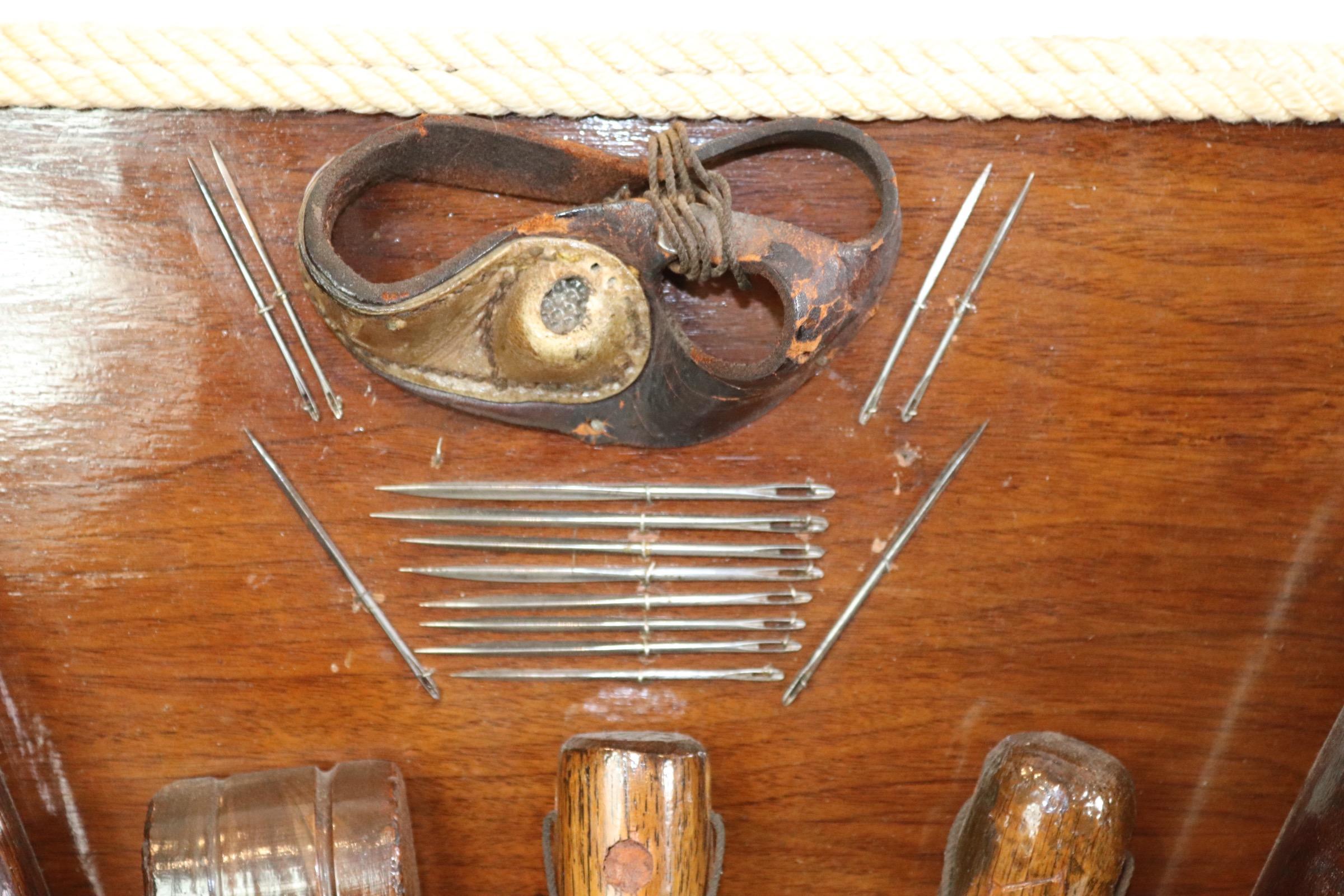 Ships rigging tools with knot work attached to a decorative wood backboard. Tools include wood mallet, awls, needles, punch, seamer, and intricate knot work. Weight is 30 pounds.