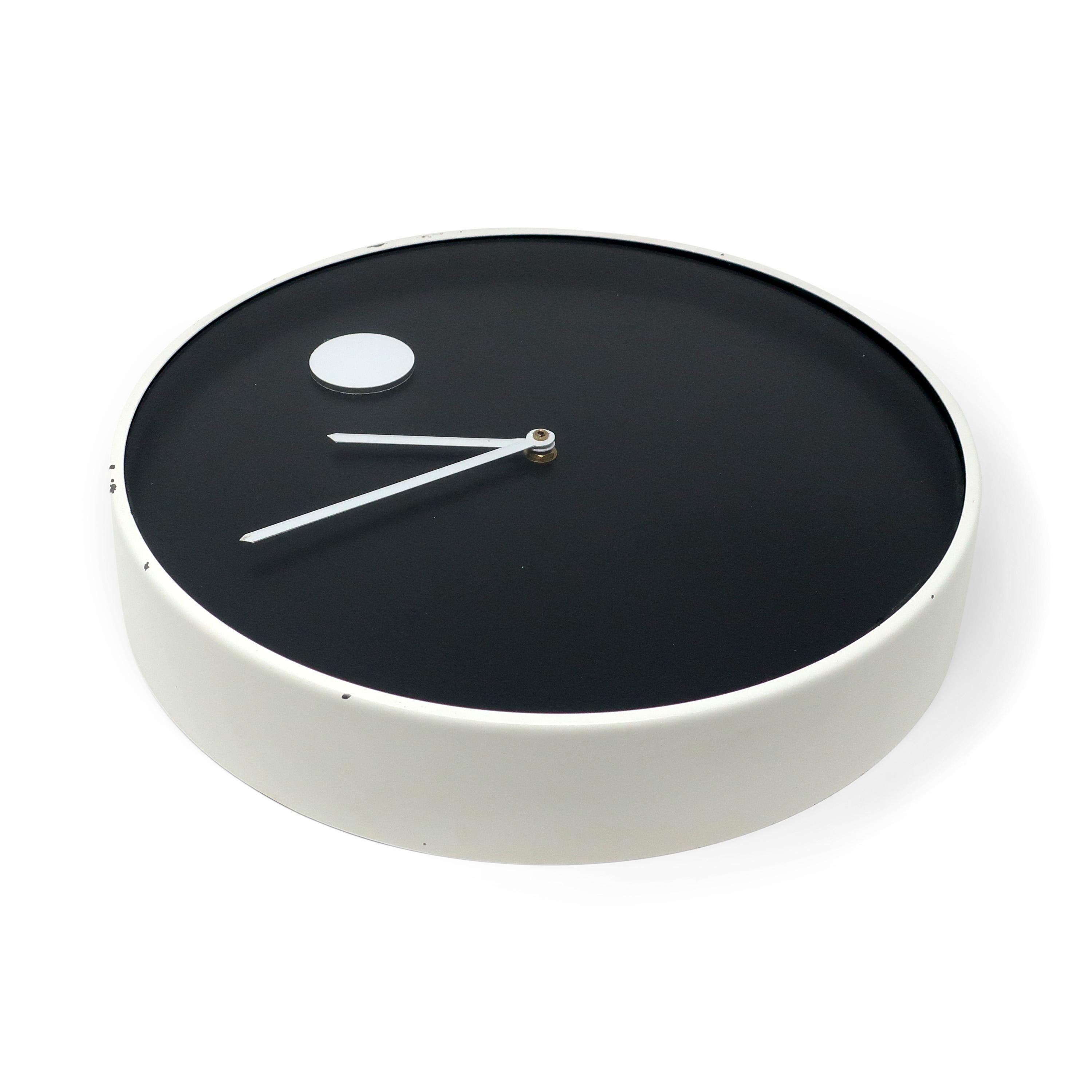 A minimalist black and white wall clock designed by Nathan George Horwitt for Howard Miller. Metal white enameled case, white hands, black face, white dot at the 12 o’clock position. and glass front. Included in the 1970's design collection of the