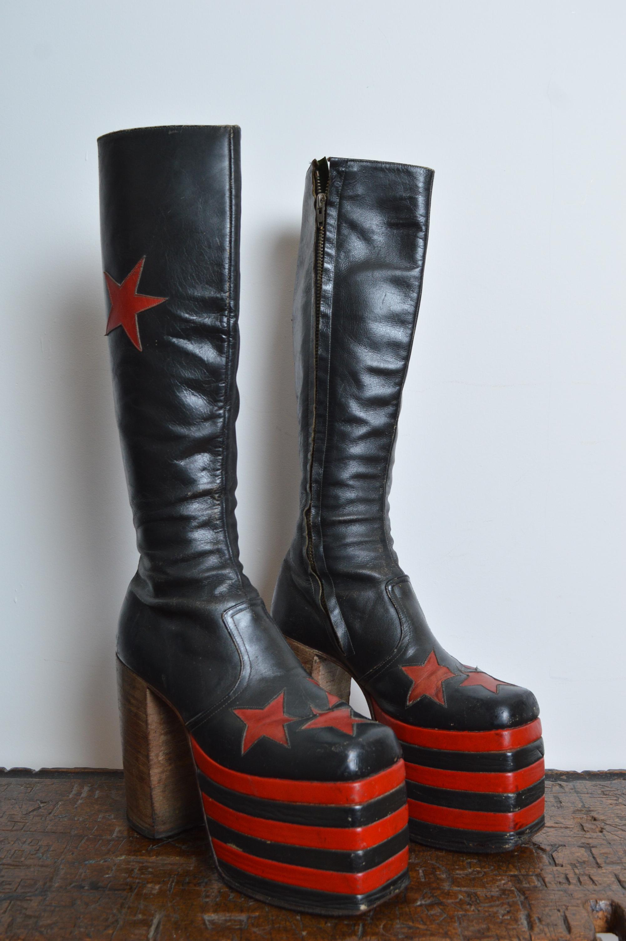 Museum Worthy 1970's Glam Rock leather Red & Black Platform Boots UK 6 / EU 39
Featuring star design with striped leather platform and wooden sole.
London (England) circa 1970.
MEASUREMENTS IN INCHES ;
Towering heel height of 5.5