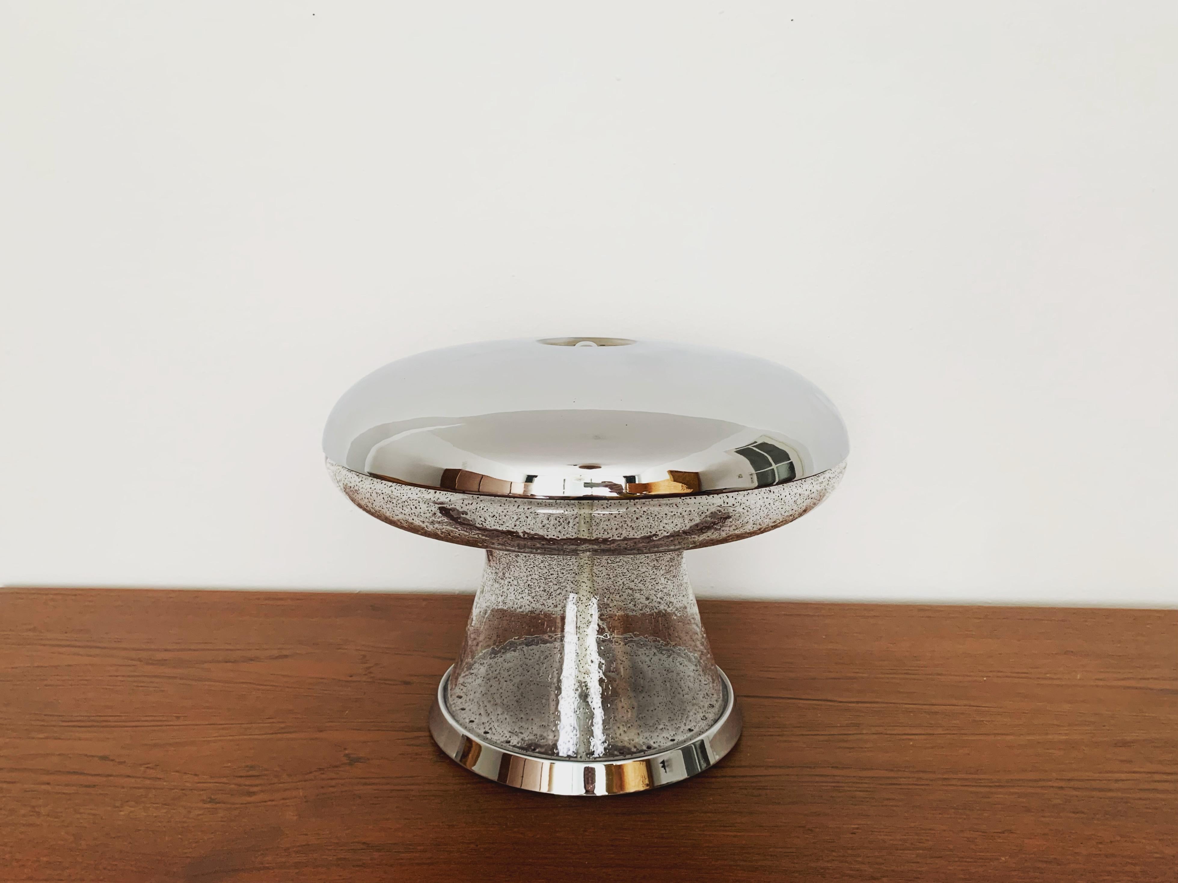 Très belle lampe de table en verre de glace de haute qualité des années 1960.
Cette lampe est très noble et constitue un objet de design très spécial.
Les inclusions rouges dans le verre créent une lumière très pétillante.

Condit :

Très bon état