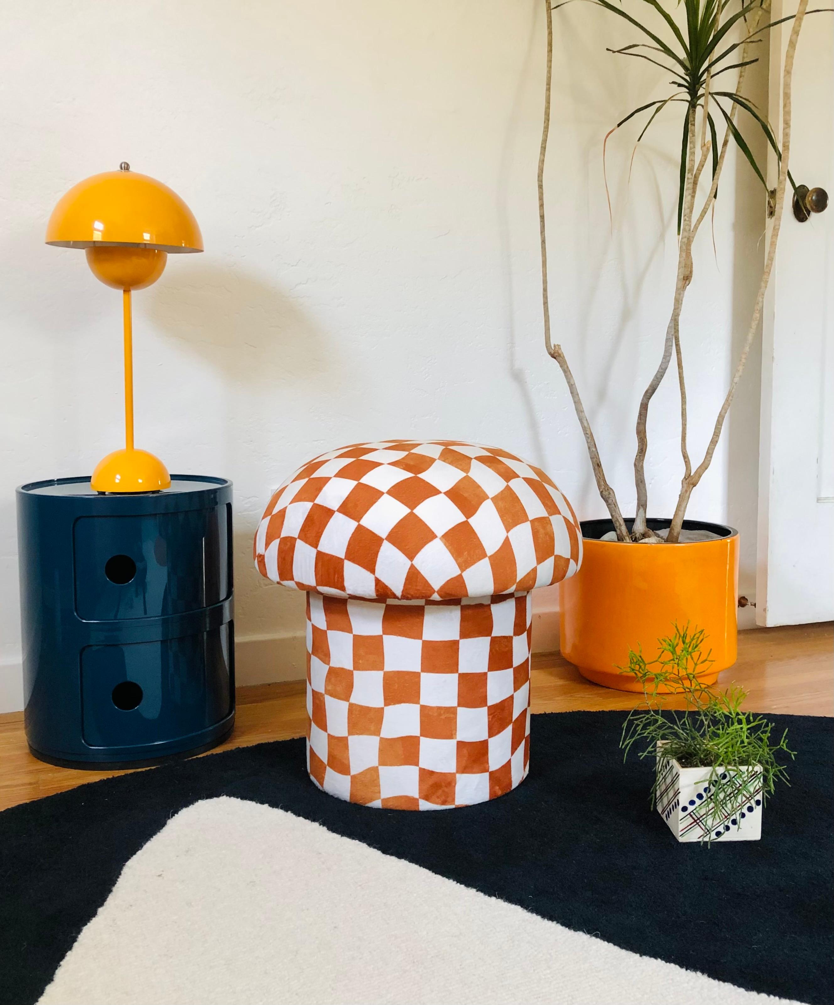 A handmade mushroom shaped ottoman, upholstered in a white and burnt orange warped checkerboard velvet fabric. Perfect for using as a footstool or extra occasional seating. A comfortable cushioned seat and sculptural accent piece.
Mushroom ottomans