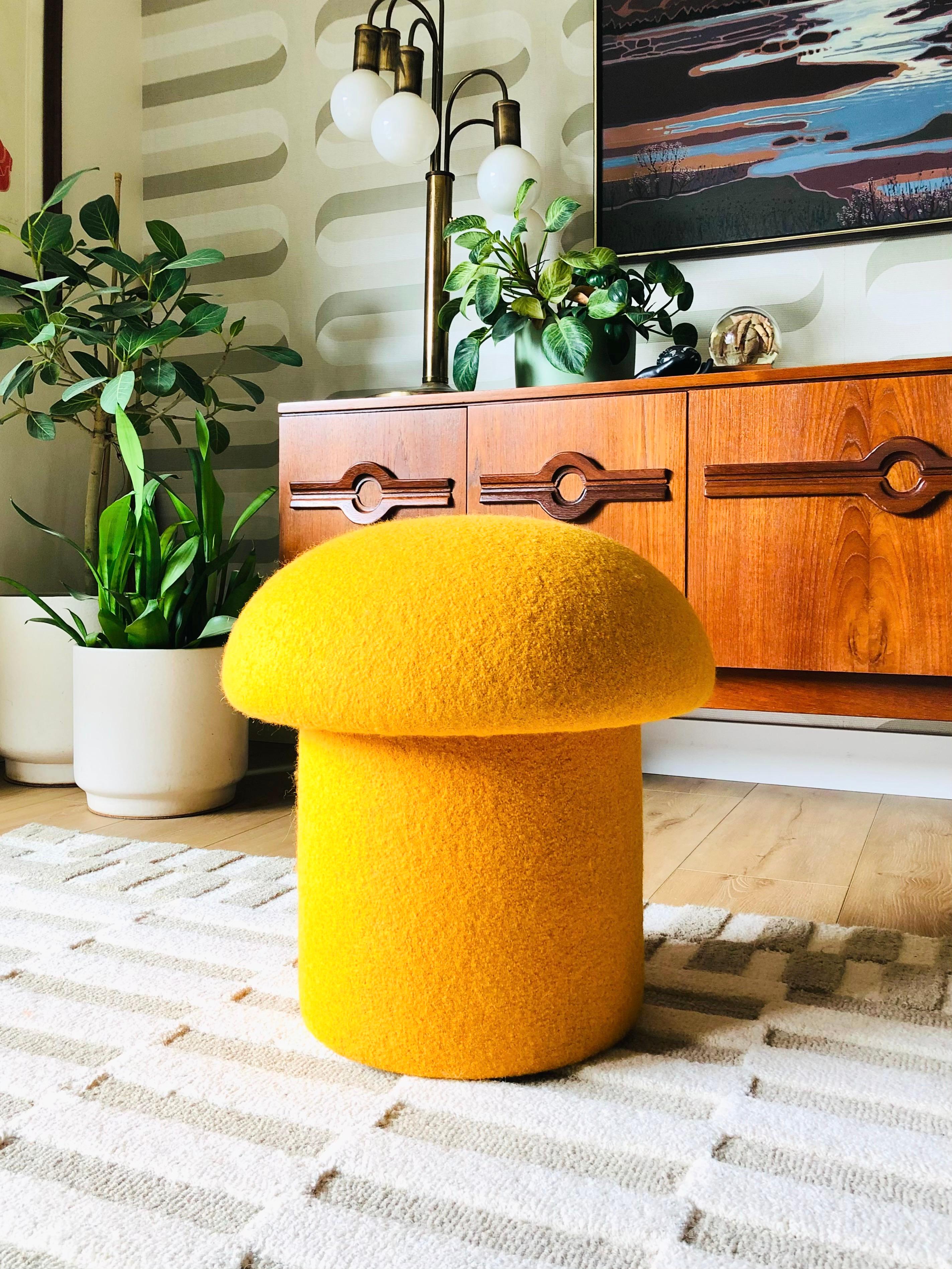 Un ottoman en forme de champignon, fait à la main, tapissé d'un tissu de laine jaune 