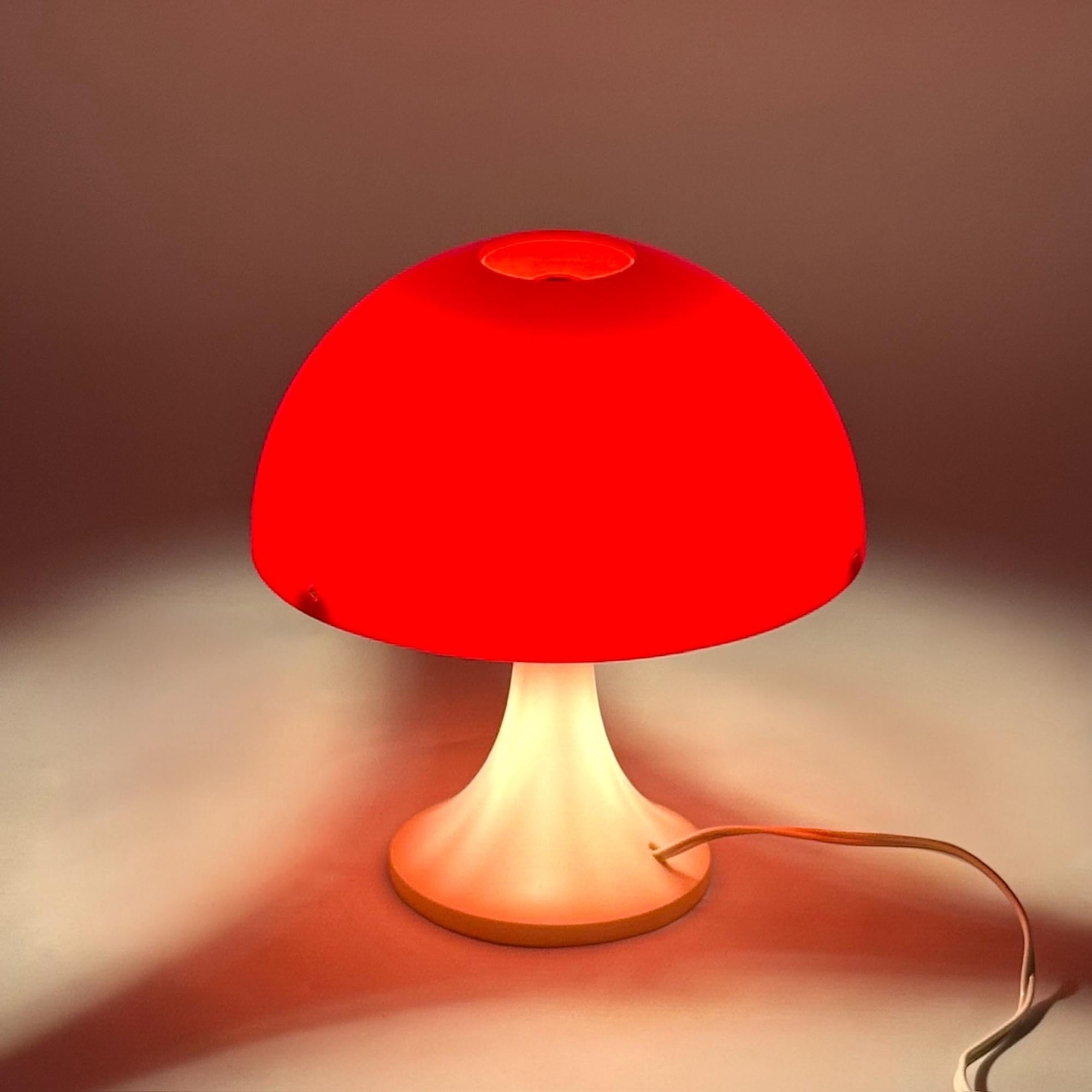 Diese originelle Pilztischlampe aus den 1970er Jahren ist ein Paradebeispiel für italienisches Space Age Design. Die Leuchte mit ihrer kräftigen roten Kuppel und dem tulpenförmigen elfenbeinfarbenen Sockel ist aus geformtem Kunststoff hergestellt