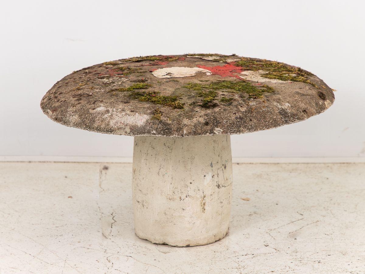 From 1960s France emerges a delightful Mushroom Toadstool Garden Ornament or Cocktail Table, boasting a vivid red cap adorned with charming white spots, juxtaposed against a timeworn white concrete base. This whimsical creation seamlessly blurs the