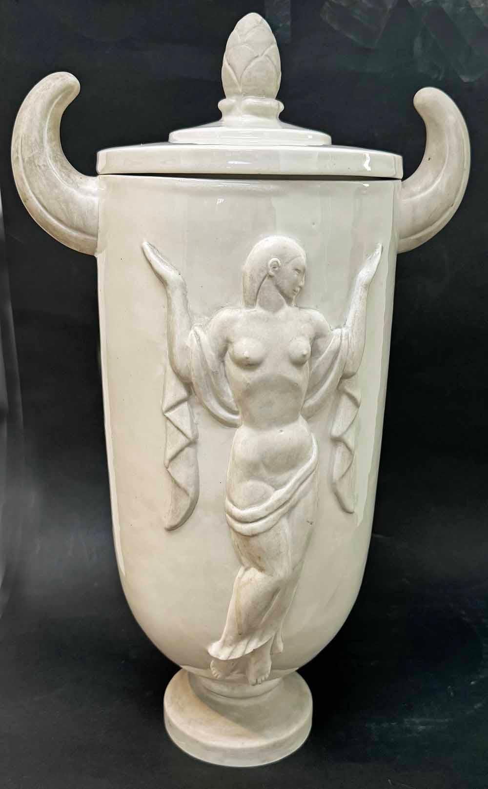 Scolpita da William Williams, uno dei maestri della scultura Art Deco in America, questa urna coperta unica nel suo genere presenta due figure femminili nude stilizzate che rappresentano la Musica e la Danza, ciascuna espressa in rilievo.   L'urna è