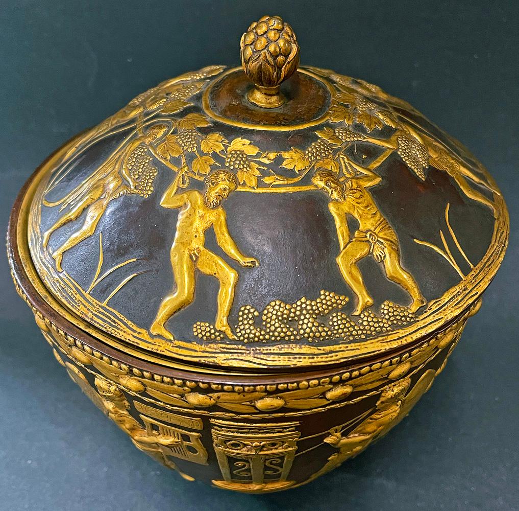 Made by Edward F. Caldwell & Company of New York, America's most distinguished and lauded maker of fine lighting fixtures and metal decorative pieces in the early 20th century, this lidded bowl of cast and repoussé bronze depicts a series of