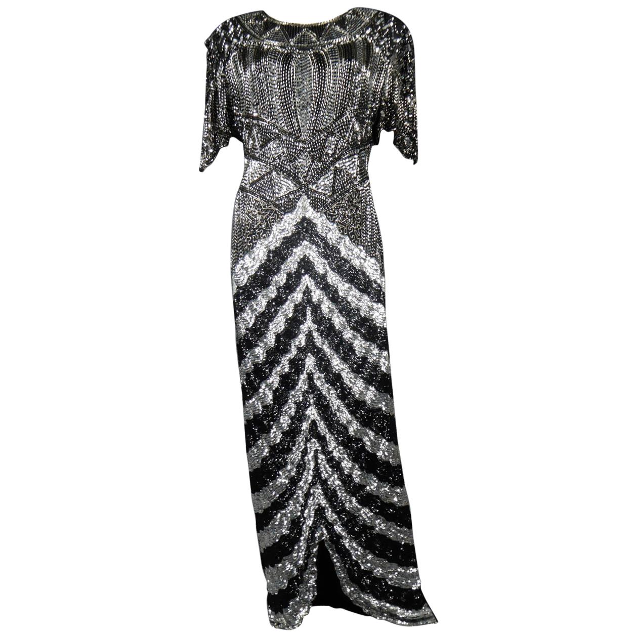 Circa 1980/1985
France

Music-Hall Evening Dress inspired by Art Deco in Silver and embroidered with black and silver faceted paillons and silver tubular pearls from the 1980s. Skin-tight dress with short flounced sleeves with small shouder pads.