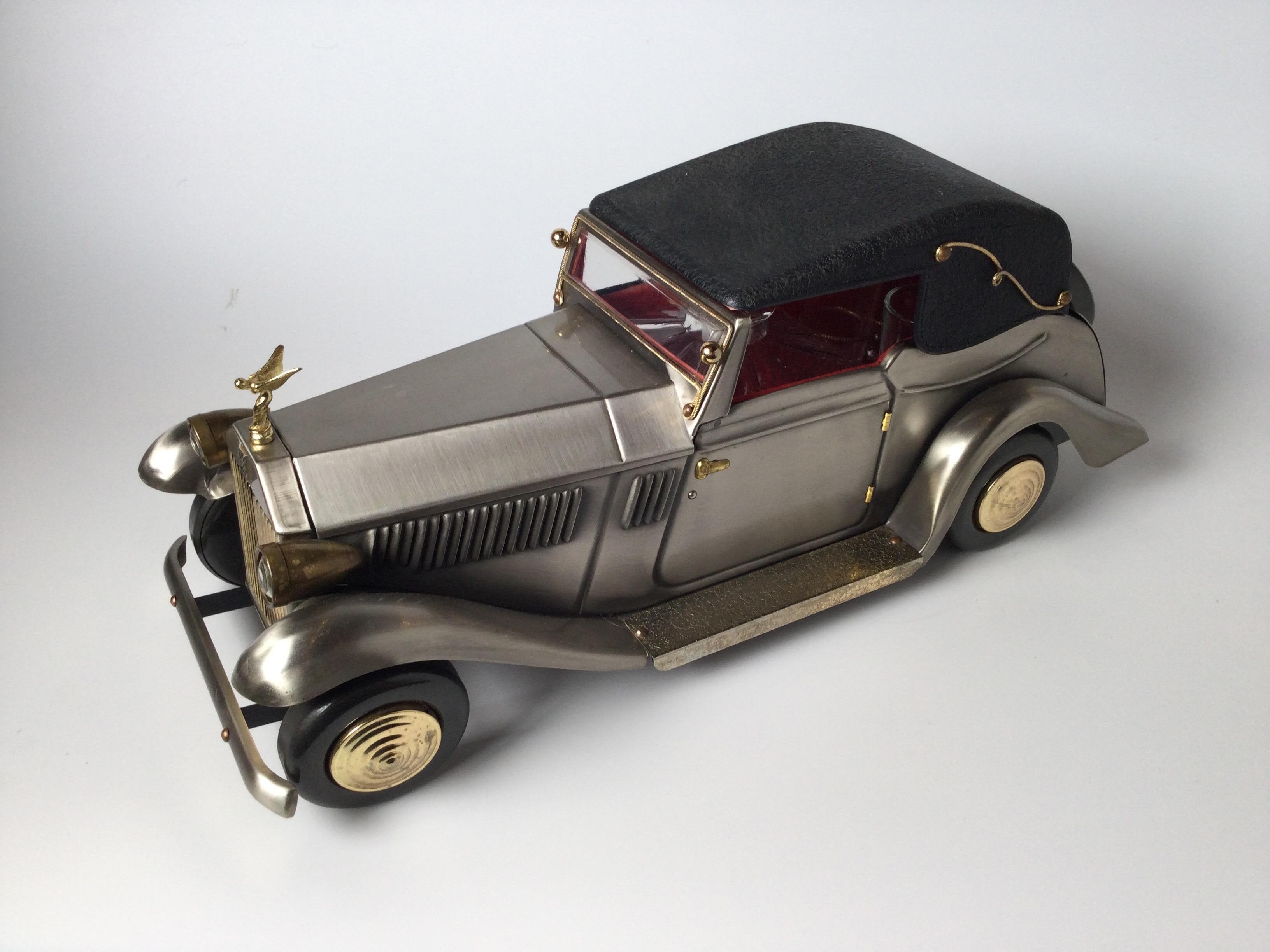 A whimsical drinks set in the form of a vintage Rolls Royce car. Set includes the car holder, with a decanter and four glasses. The car with a musical mechanism that plays around the world in 80 days.