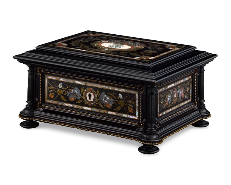 This charming musical jewelry and sewing box is a work of sublime artistry. Almost certainly German or Austrian in origin and crafted of deep, ebonized wood, this chest is adorned with an intricate inlay of engraved copper and brass accented by