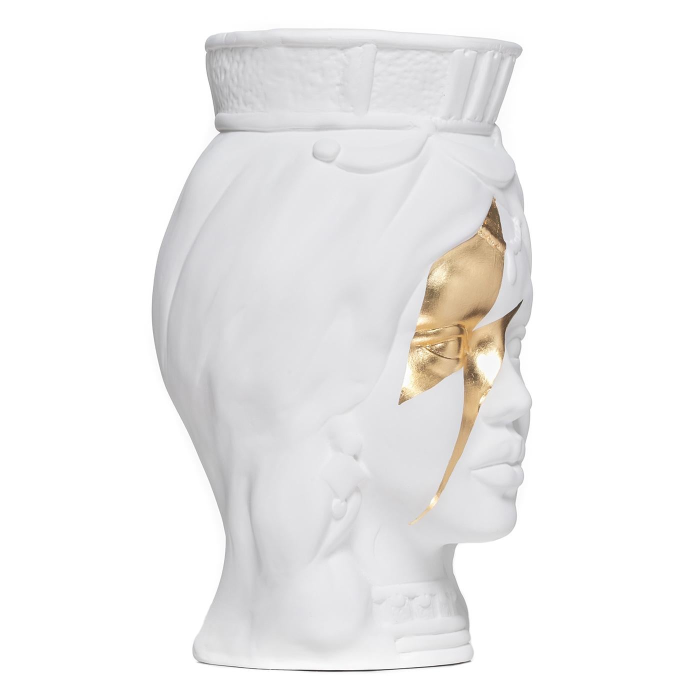 Fabriqué de main de maître en argile blanche, ce vase étonnant représente le visage d'une jeune femme parée d'une couronne et de bijoux suggérant une origine noble. Son regard captivant est renforcé par un puissant éclair en feuille d'or marquant