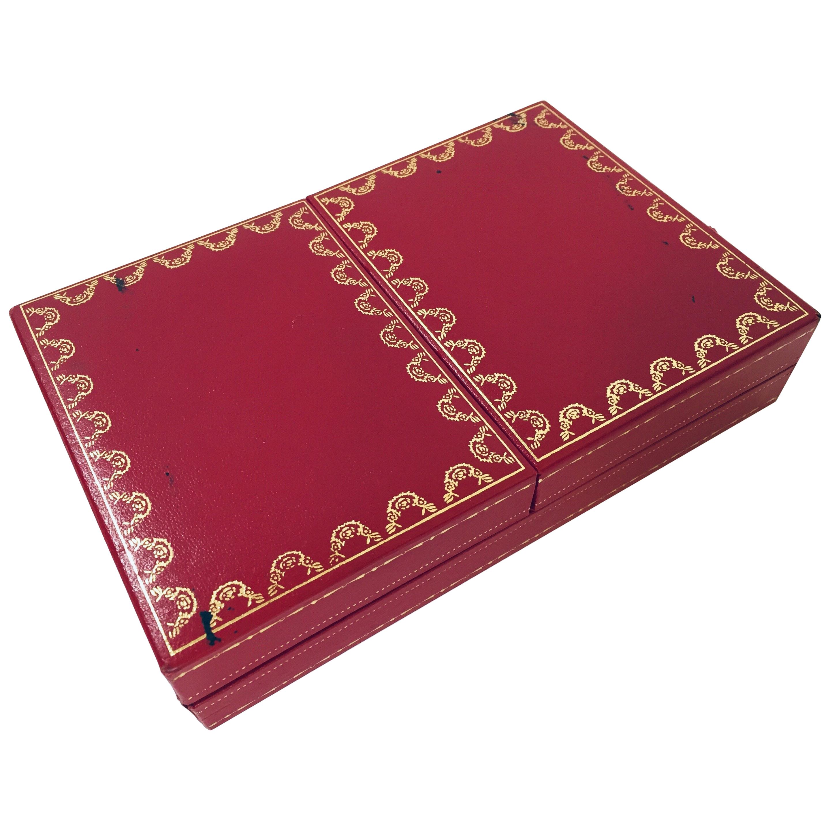 Cartier playing cards, one deck plus joker, poker, bridge playing cards in Cartier red 2-doors case.
Les Must de Cartier playing cards were only sold from 1972-1976. 
This silk-lined box of cards with 18k gilted corners, printed with the Les Must de