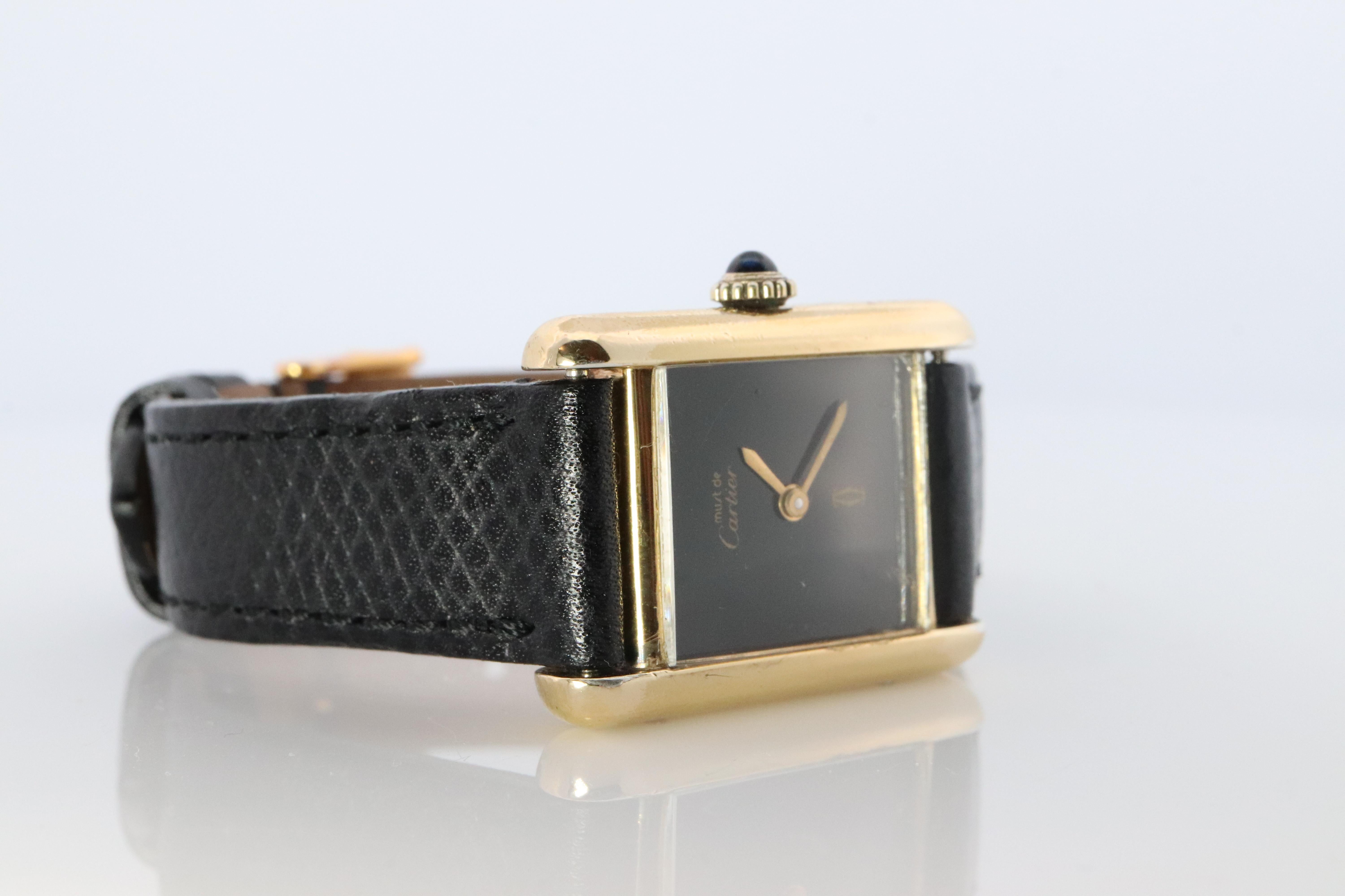 Genuine Cartier watch. Vintage Iconic Tank Argent. Sterling Silver and Gold plated (Vermeil).

RARE Black Mystery Dial.

Manual Windup Movement

New Leather Band.

Manual Movement just serviced.
Condition: Winds up and keeps time.

Details:
21mm by