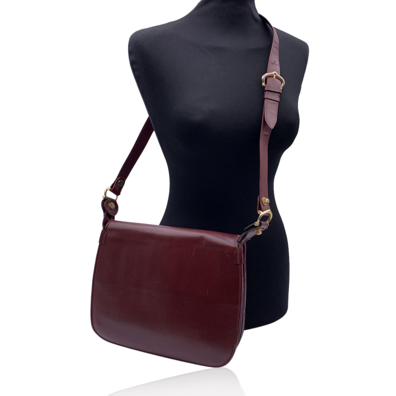 Vintage Must de Cartier shoulder bag in Burgundy genuine leather. Cartier logo patch under the flap. Gold metal hardware. 2 main compartments inside. Burgundy leather lining . Adjustable shoulder strap. 'Les Must de Cartier' tag