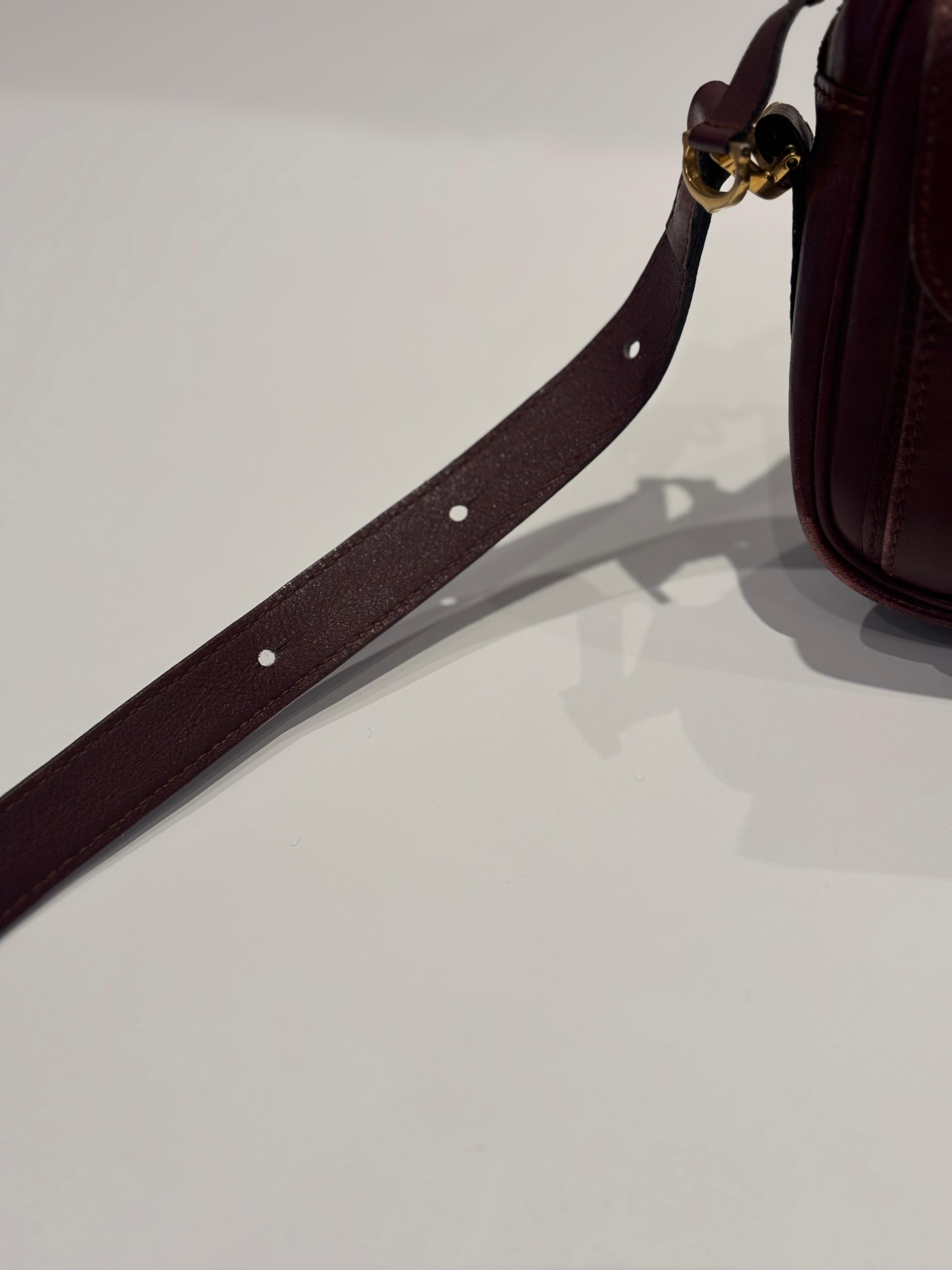 This is an iconic Cartier bag . This crossbody bag features a bordeaux leather body, a front exterior flap pocket, an adjustable flat leather strap, a Cartier logo, a top zip closure, an interior zip pocket and a Cartier graphic lining.

It has been