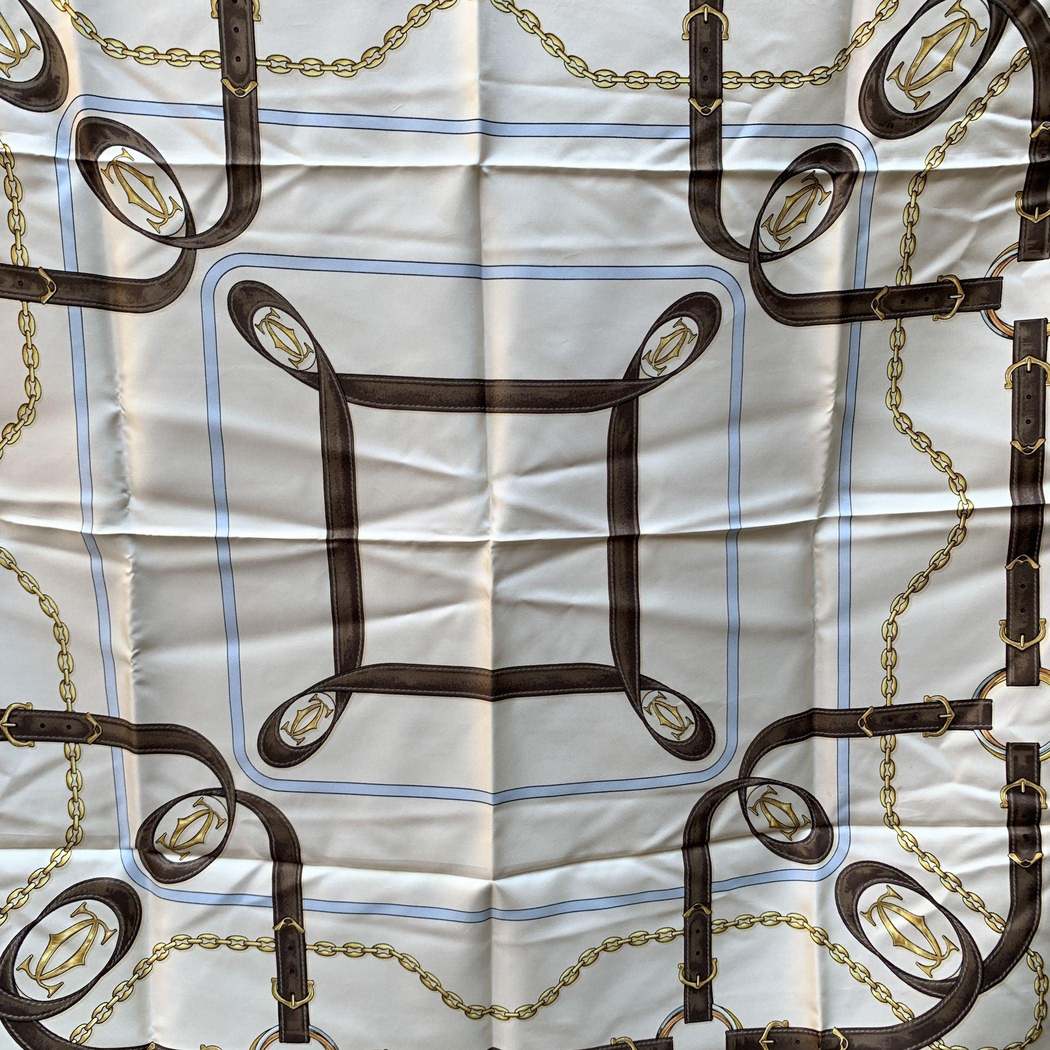 Elegant Cartier scarf in white, light blue, yellow with brown borders. Equestrian design. 'Les Must de Cartier'printed on the scarf. 100% Silk. Hand rolled edges. Condition B - VERY GOOD Some pulled threads due to norma luse. Some light darkness due