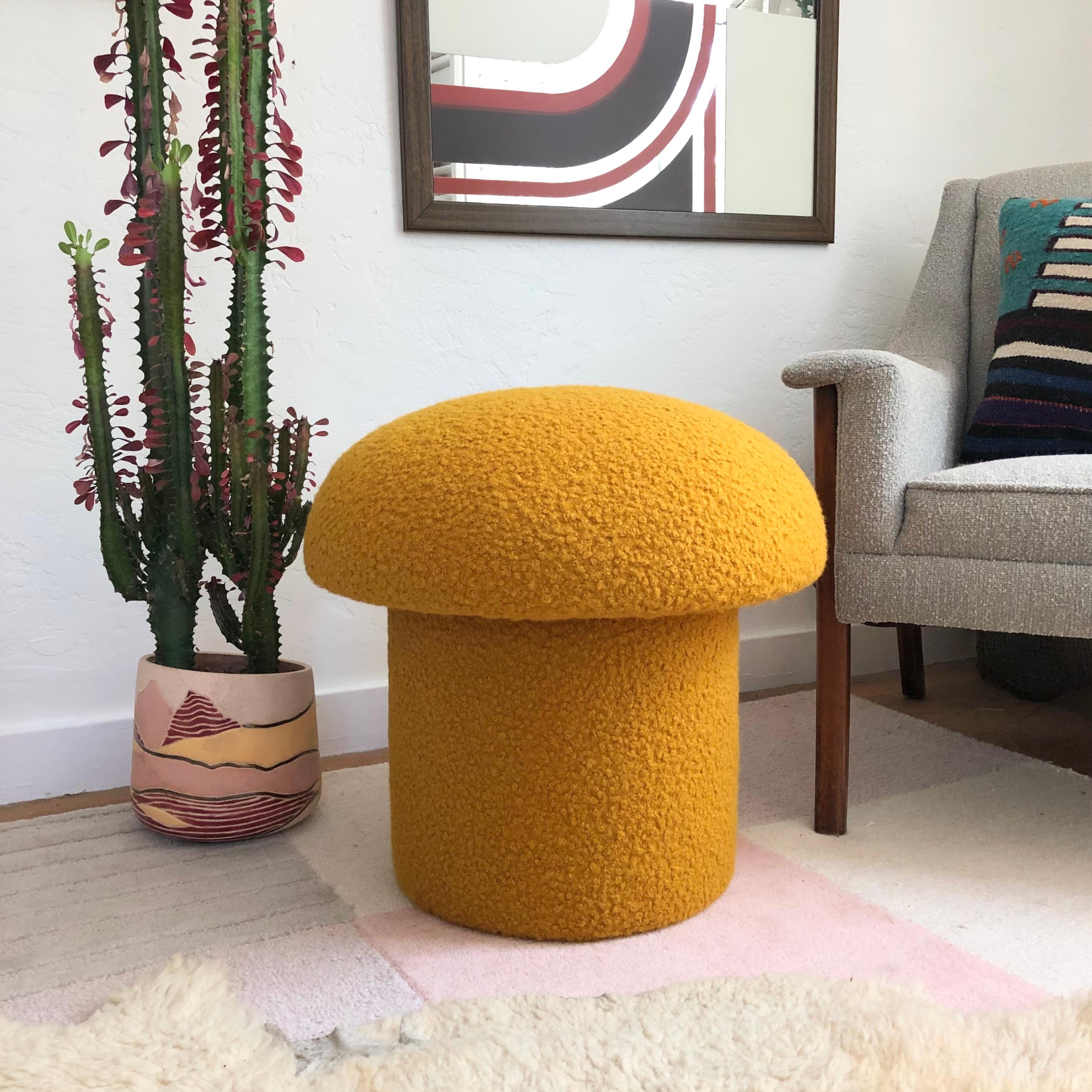 A handmade mushroom shaped ottoman, upholstered in a mustard colored curly boucle fabric. Perfect for using as a footstool or extra occasional seating. A great sculptural accent piece.