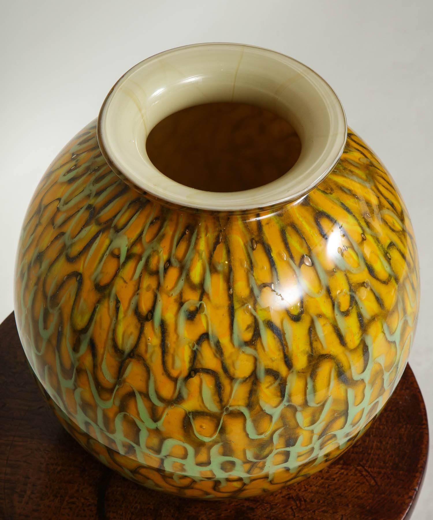 A vase with pale green and sable sinuous ribbon pattern decoration on mustard yellow ground of globe form, made of heavy glass.