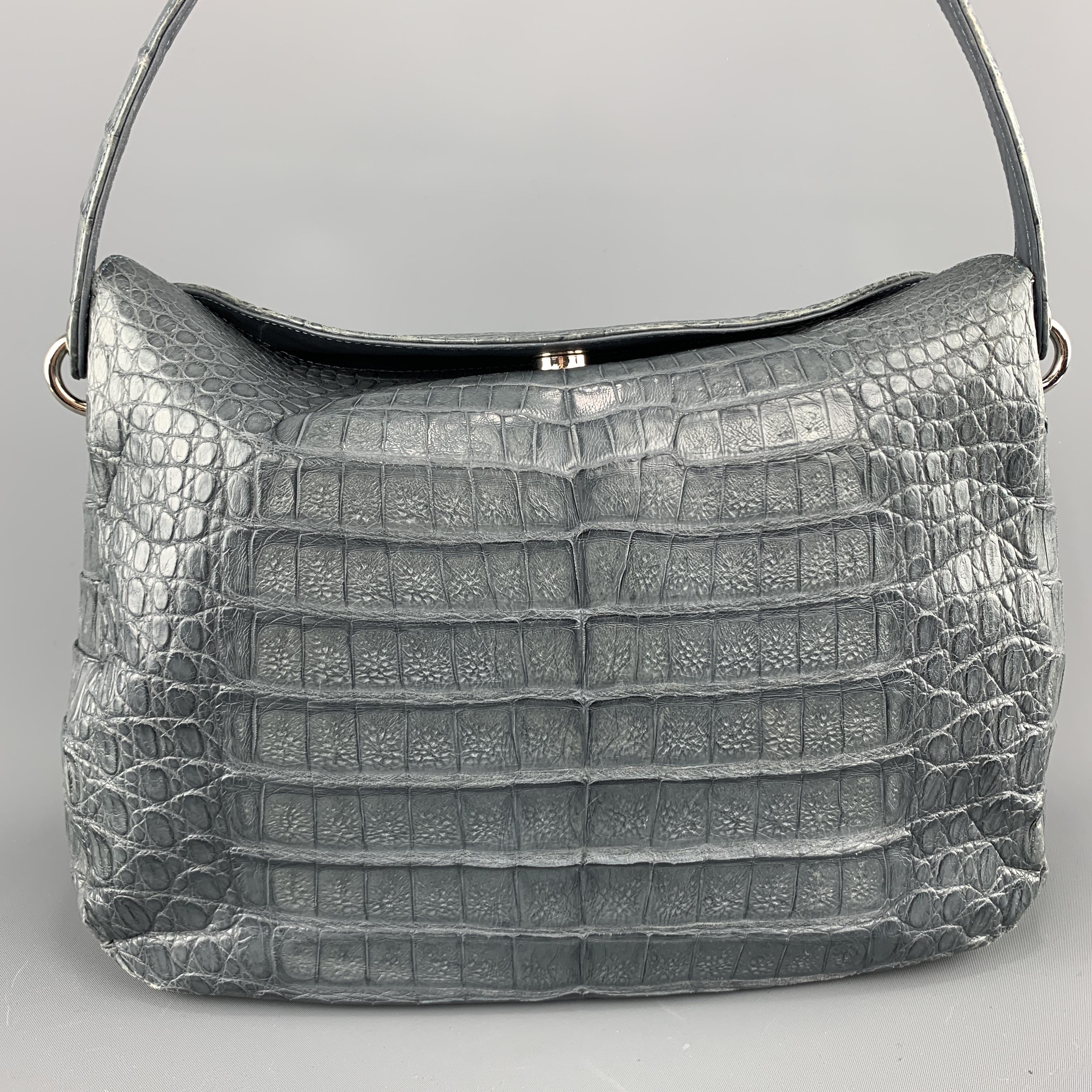 Structured shoulder bag comes in a gorgeous muted blue slate gray authentic crocodile skin leather with silver tone grommet hardware, top fold snap closure, and taupe suede interior.
 
Very Good Pre-Owned Condition.
 
Measurements:
 
Length: 12.5