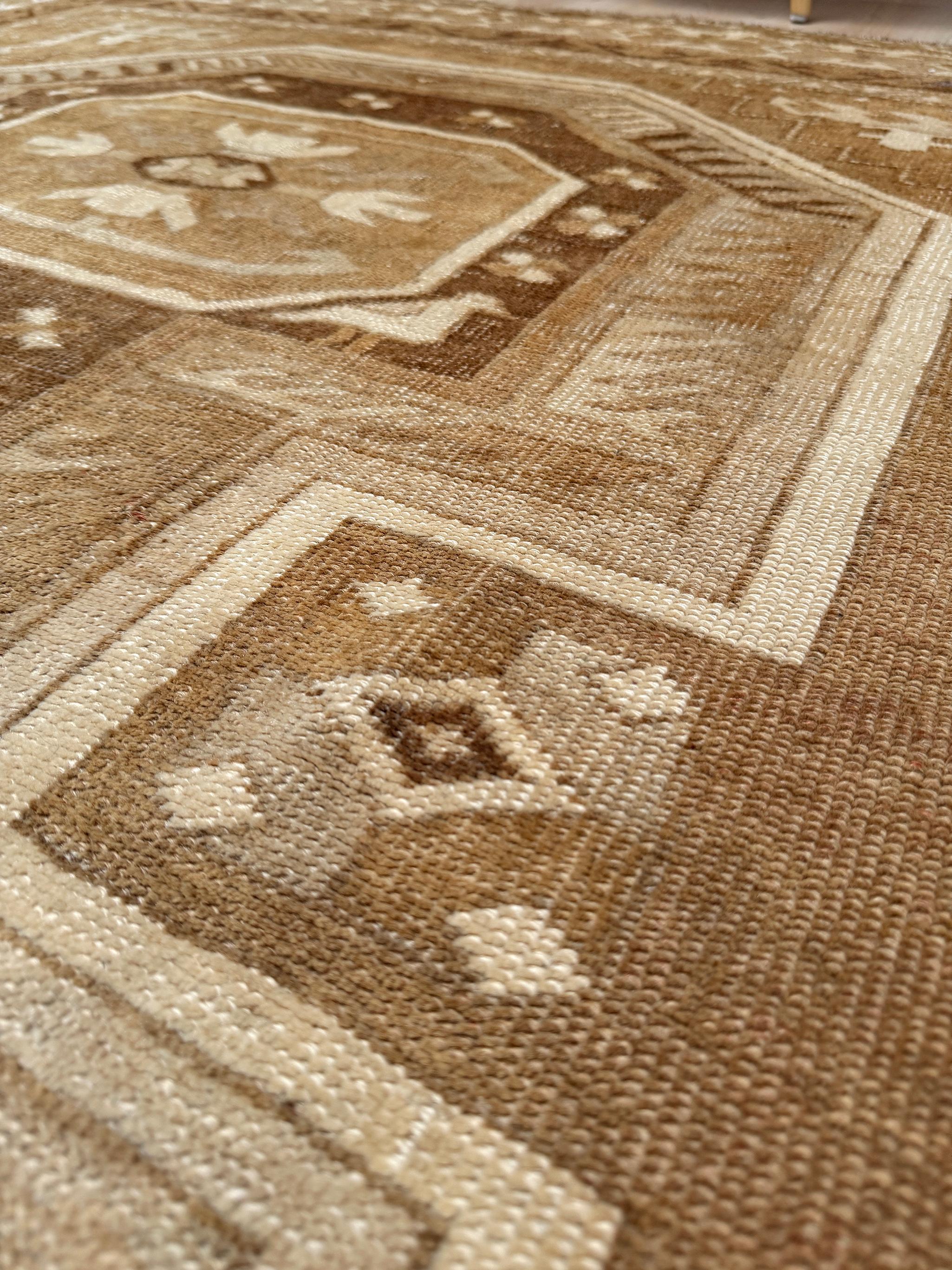 Questo tappeto vintage curdo di Kars è una vera e propria masterclass nell'eleganza silenziosa: una miscela serena di arenaria, tortora e marrone tenue che evoca il calore di un tramonto anatolico. Tessuto in lana di Kars, lucida e filata a mano,