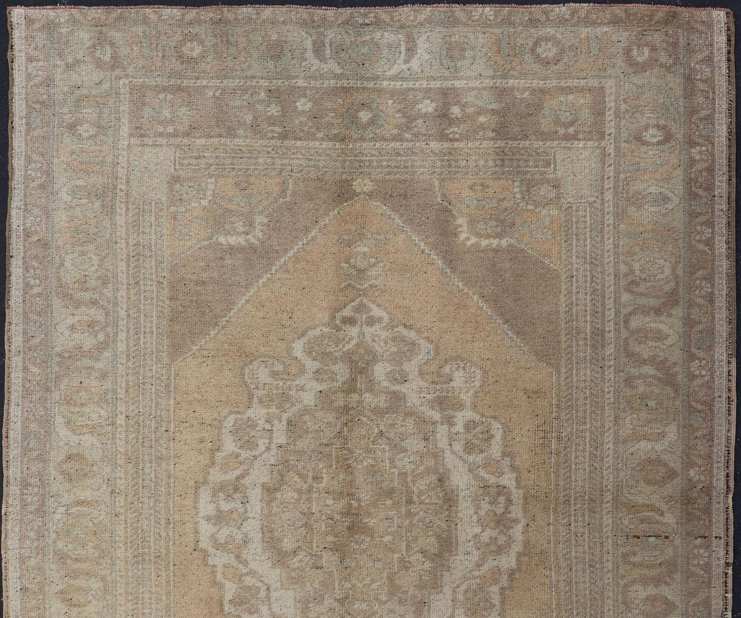 This muted 1940's Turkish Oushak carpet features a design with multi shades of muted colors. The border features repeating flowers and vines rendered in light blues, grays, muted brown and taupe colors.

Measures: 5'1 x 7'5
 Muted vintage Turkish