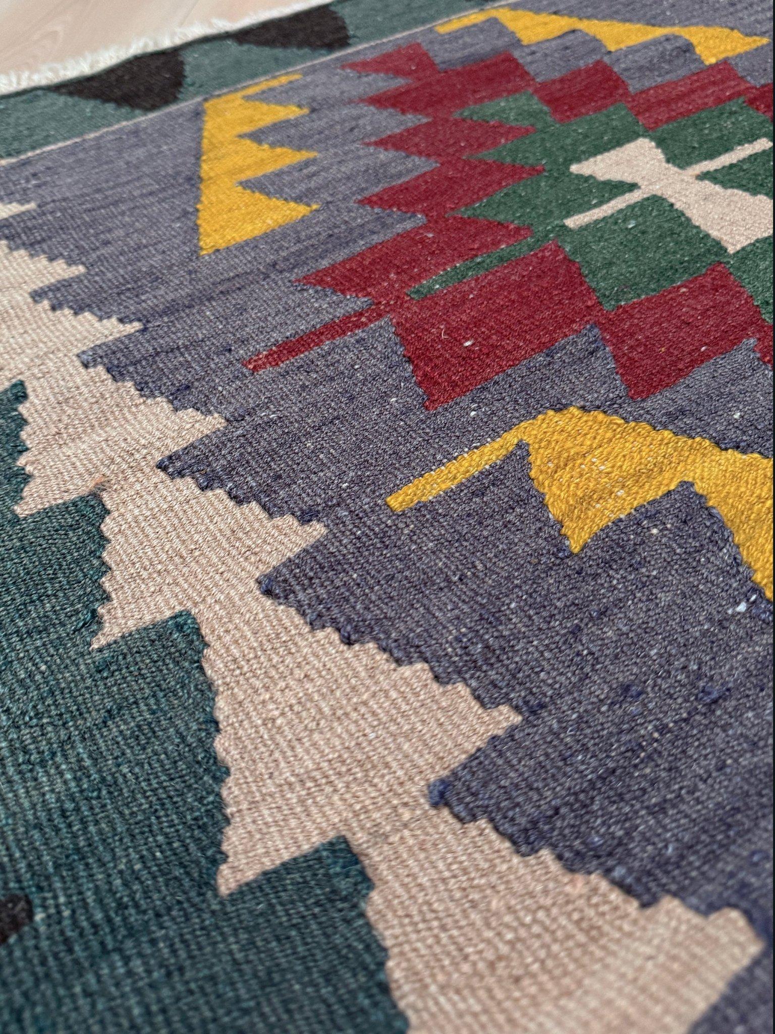 Questo kilim turco in stile Navajo fonde l'artigianato anatolico con un'audace sensibilità geometrica di metà secolo. Tessuto a mano con lana filata a mano su una base di cotone, presenta un dinamico medaglione a diamante affiancato da motivi