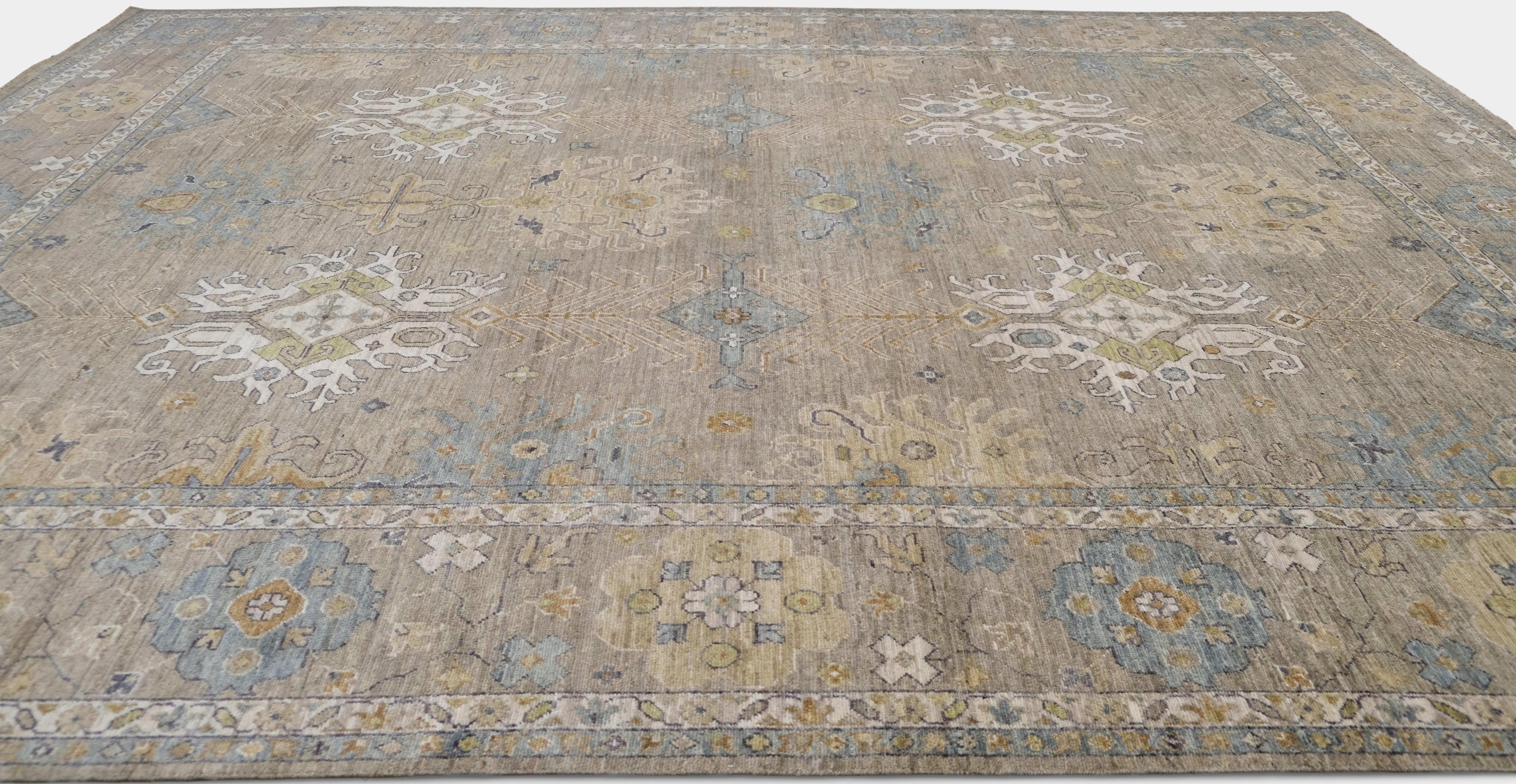 Ce tapis Oushak en laine nouée à la main est d'une élégance intemporelle. Il présente un motif floral et géométrique raffiné en médaillon dans des tons doux de beige, de taupe et de bleu sourd. L'équilibre délicat entre le design traditionnel et